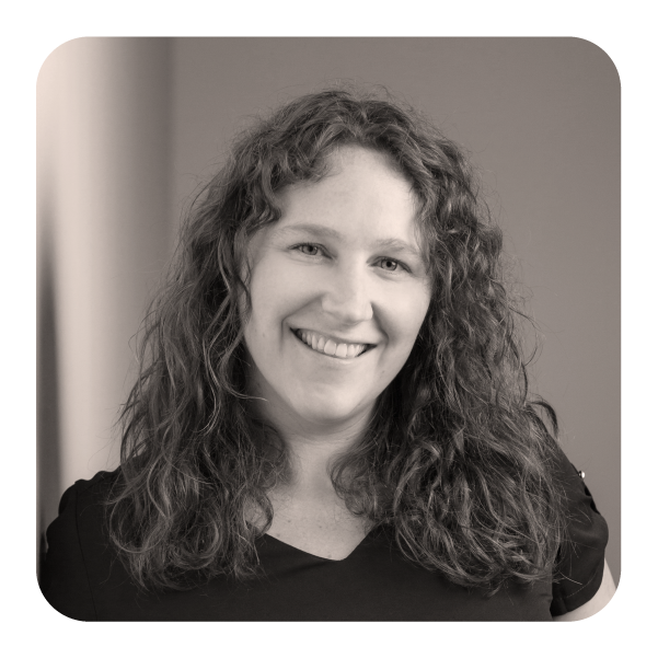 Black and white photo of a woman with curly hair smiling at the camera.