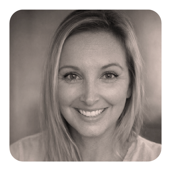 A woman with long light-colored hair smiling at the camera in a black and white portrait.