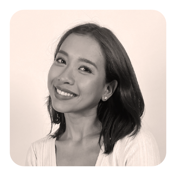 A woman with shoulder-length hair, smiling and looking at the camera, wearing a light-colored top, in a black-and-white portrait.
