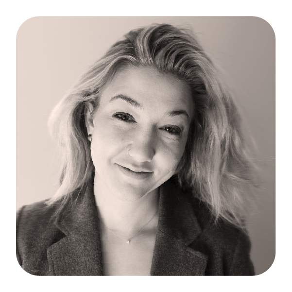 Black and white photo of a woman with blonde hair, smiling gently, wearing a blazer.