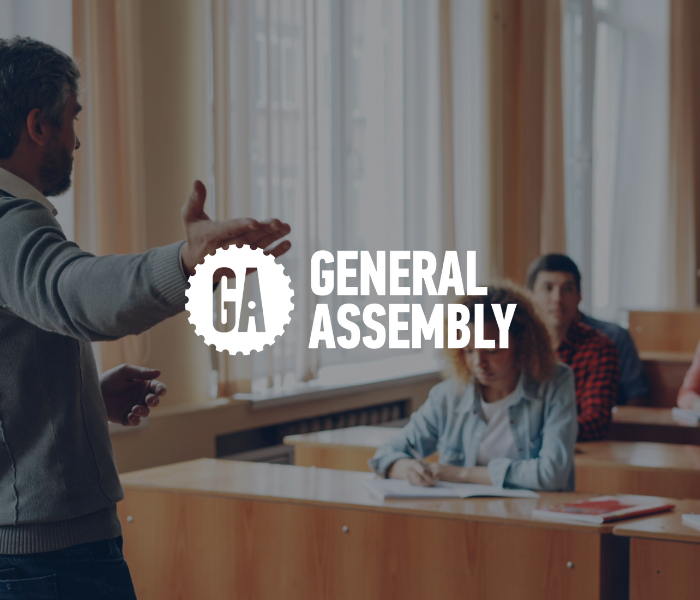 A man gestures while standing in front of students in a classroom, with a logo and text overlay that reads 'General Assembly'.