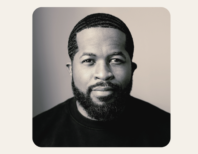 Black and white portrait of a man with black hair and a beard smiling gently