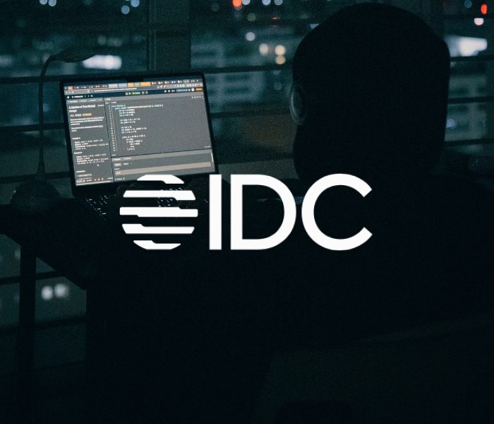 A person working on a laptop at night, with the letters 'IDC' and a globe logo on the image.
