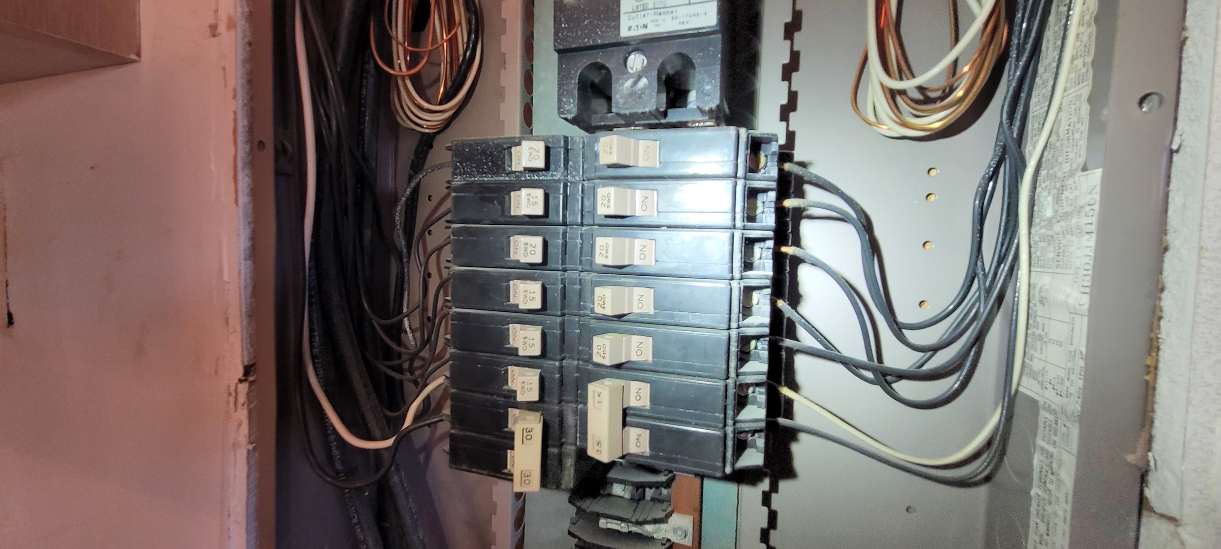 Electrical panel with circuit breakers, wires, and labels. Arc Light Home Inspections