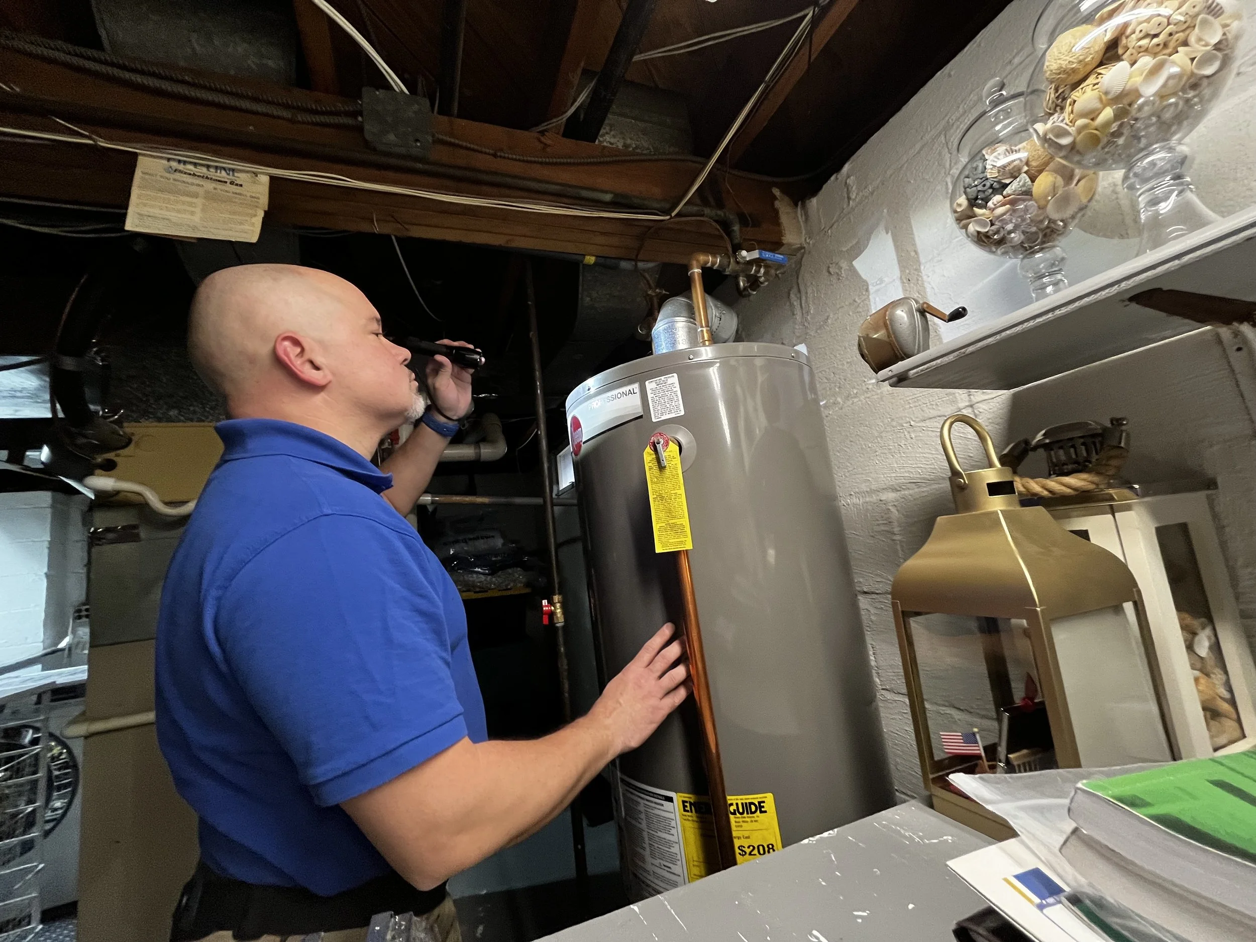 James Morales from Arc light home inspections performing a residential home inspection inspecting a water heater in a basement or utility room.