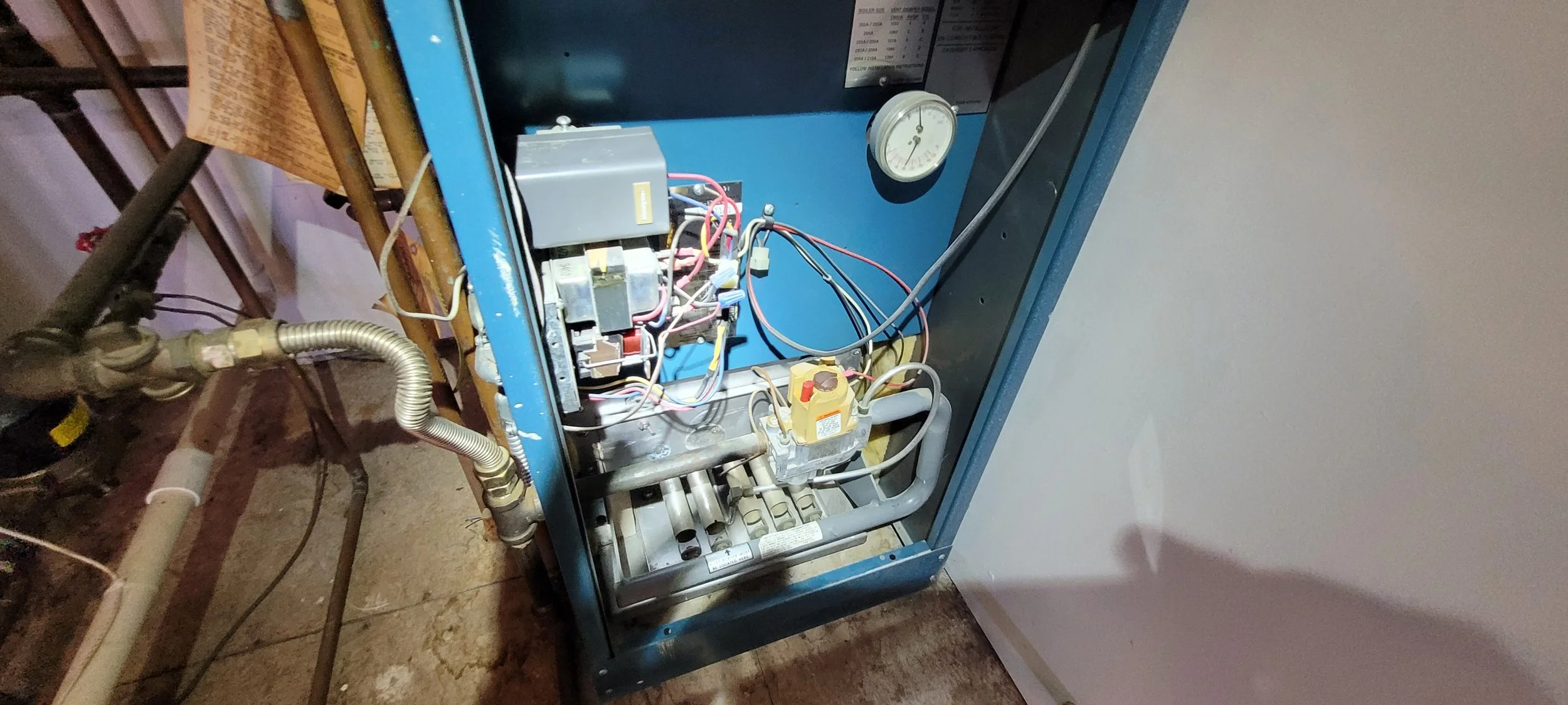 Open HVAC or refrigeration unit with visible electrical components, wires, and pressure gauge inside a metal cabinet. Arc Light Home Inspections