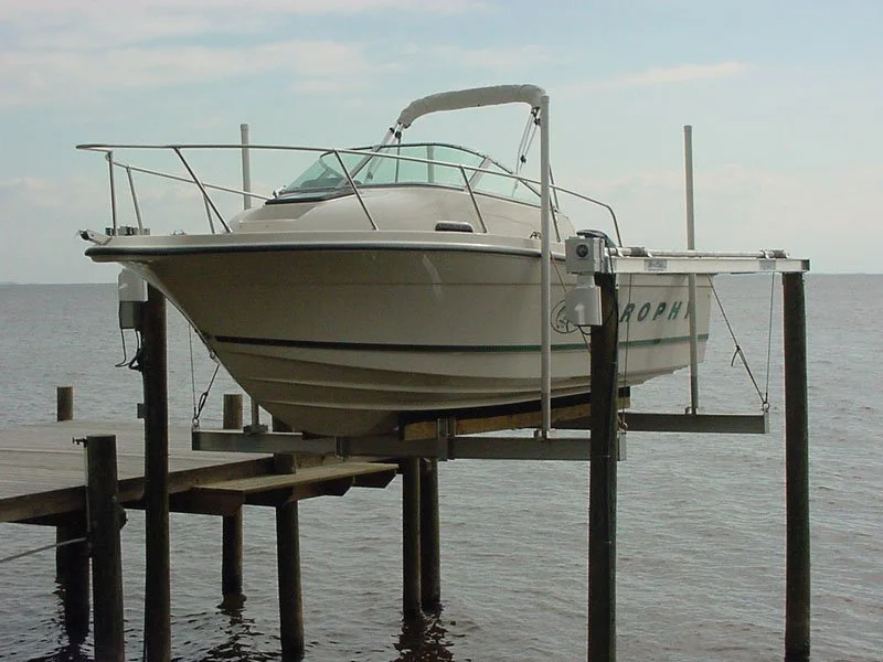 A white motorboat on a wooden dock over water under a partly cloudy sky.