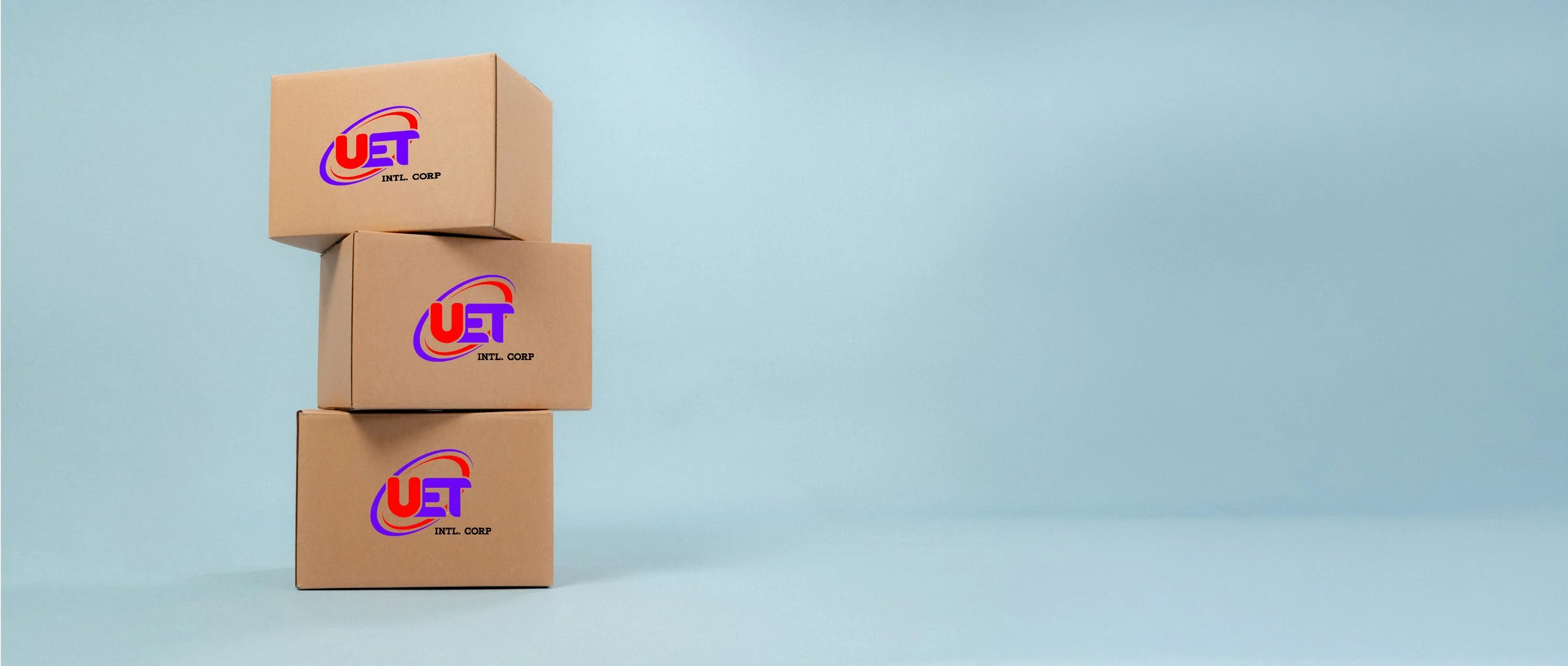 Three cardboard boxes stacked vertically on a light blue background, each with a logo that reads 'UET' in red and blue with black text 'INTL. CORP' below.