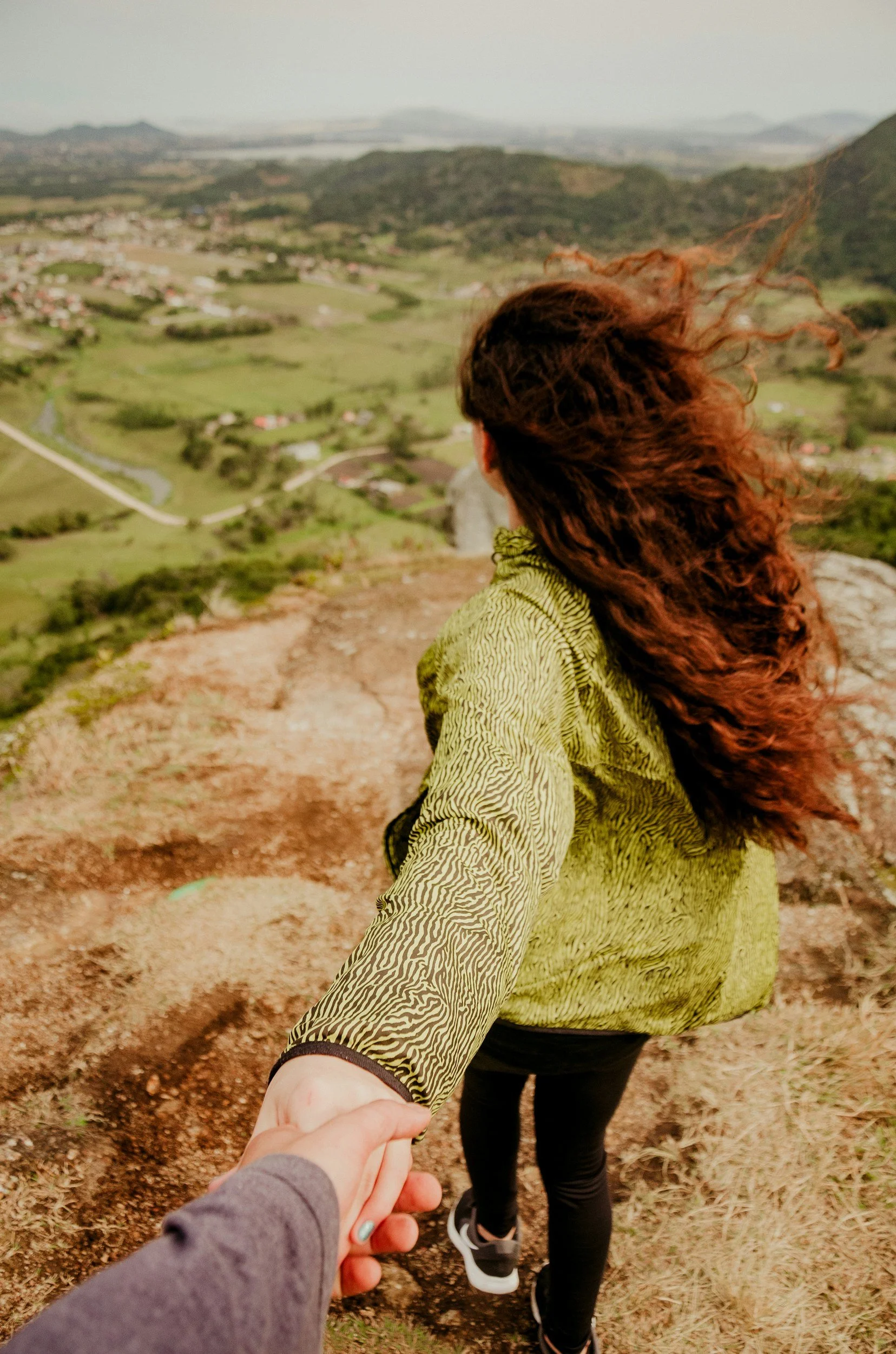 Frau führt ihren Partner an der Hand durch eine Landschaft – Symbol für Vertrauen, Nähe und gemeinsame Lebensrichtung