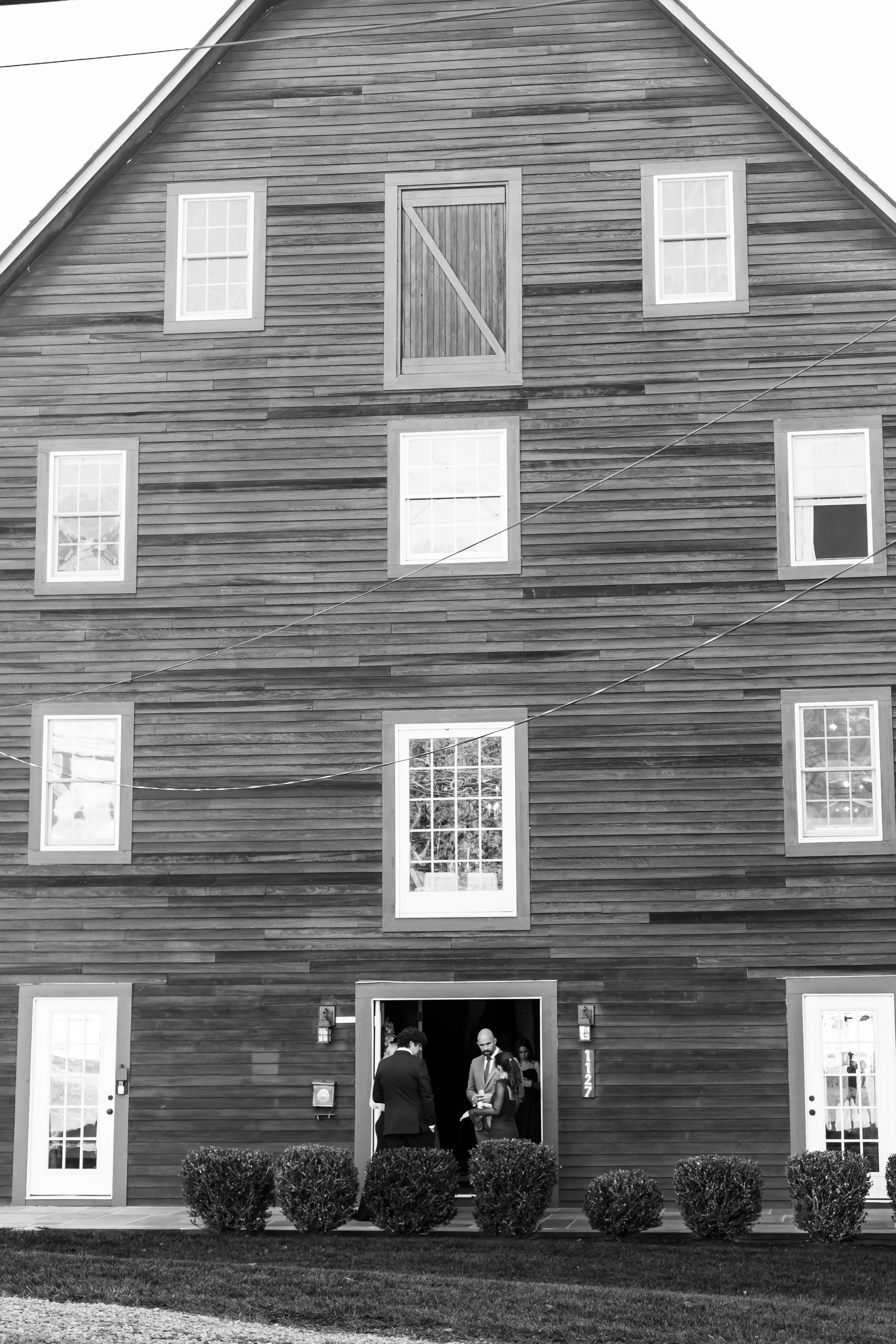 People gathered at the entrance of a large wooden grist mill for an event in Neshanic Station, NJ.