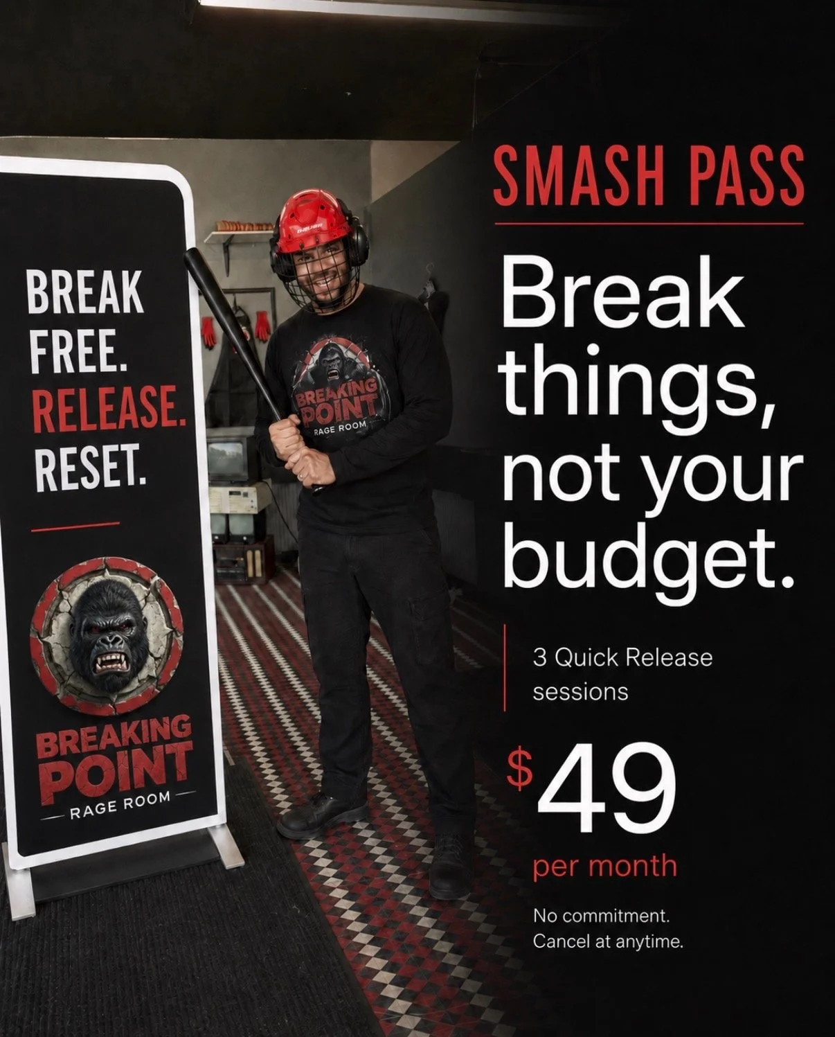 A man standing with a bat and wearing a red safety helmet and black tshirt with the breaking point logo