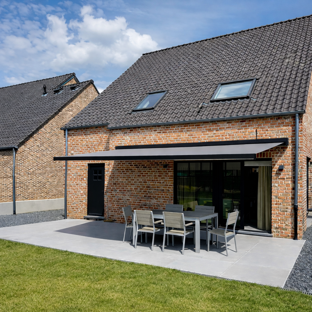Backyard patio with outdoor dining table and chairs in front of brick house with large sliding glass doors, small lawn, and neighboring brick house under partly cloudy sky.