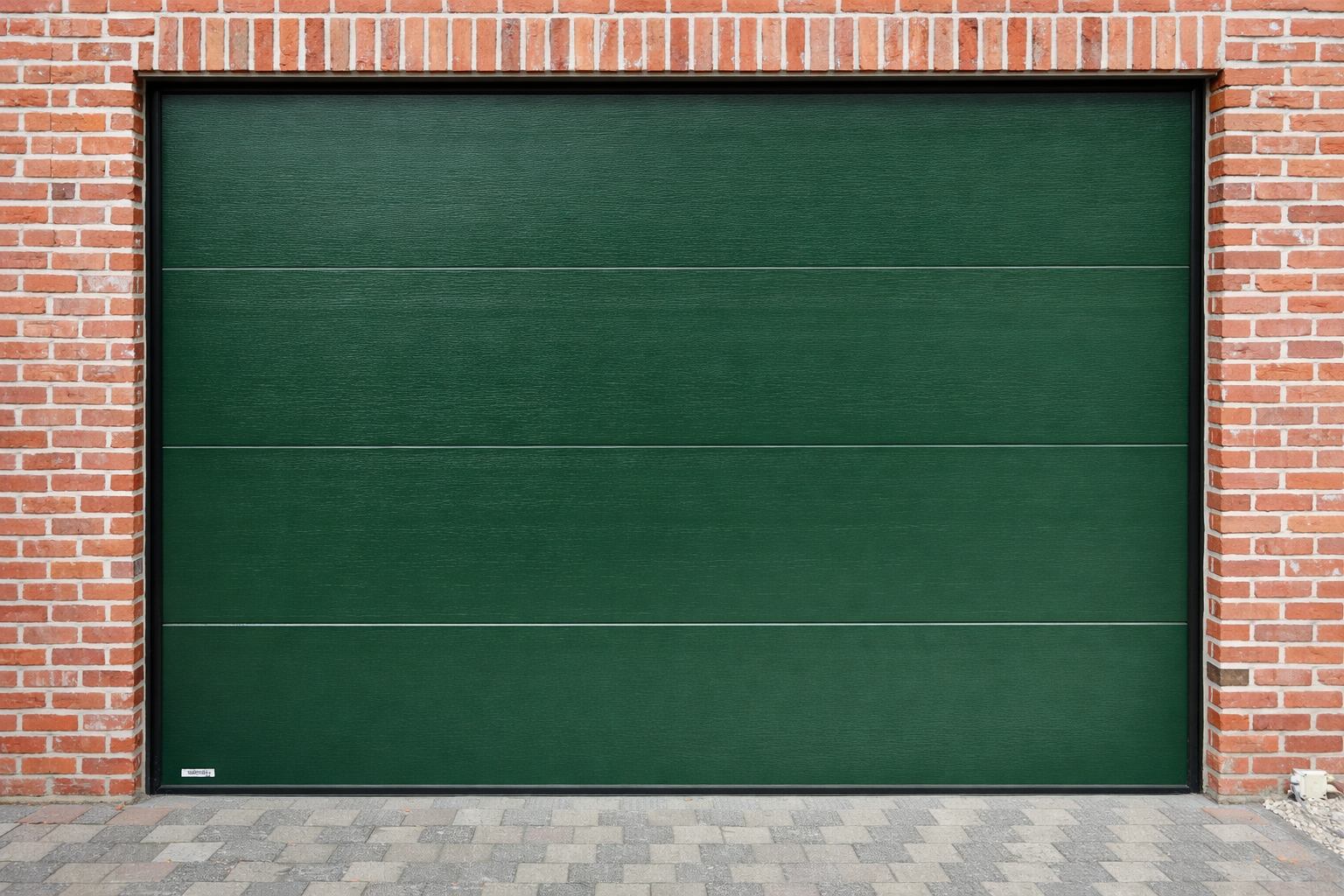 Green garage door with horizontal panels, set in a brick wall, with a paved driveway in front.