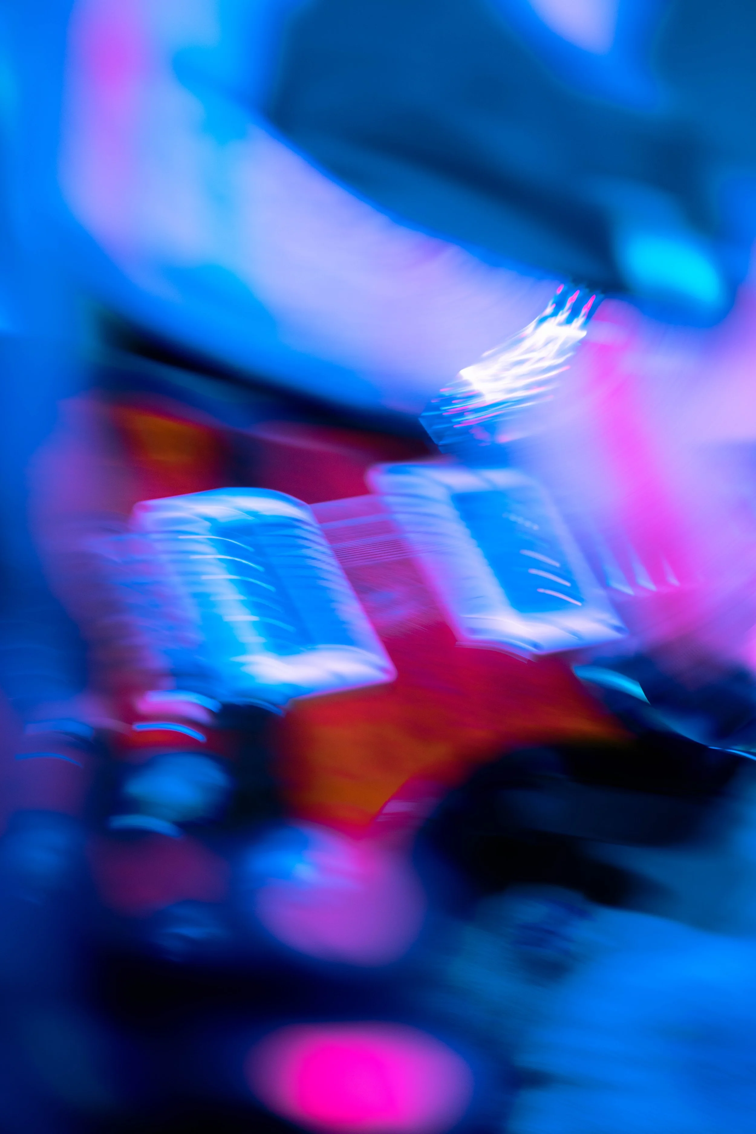 Blurry image of a person using a laptop computer with colorful lighting.