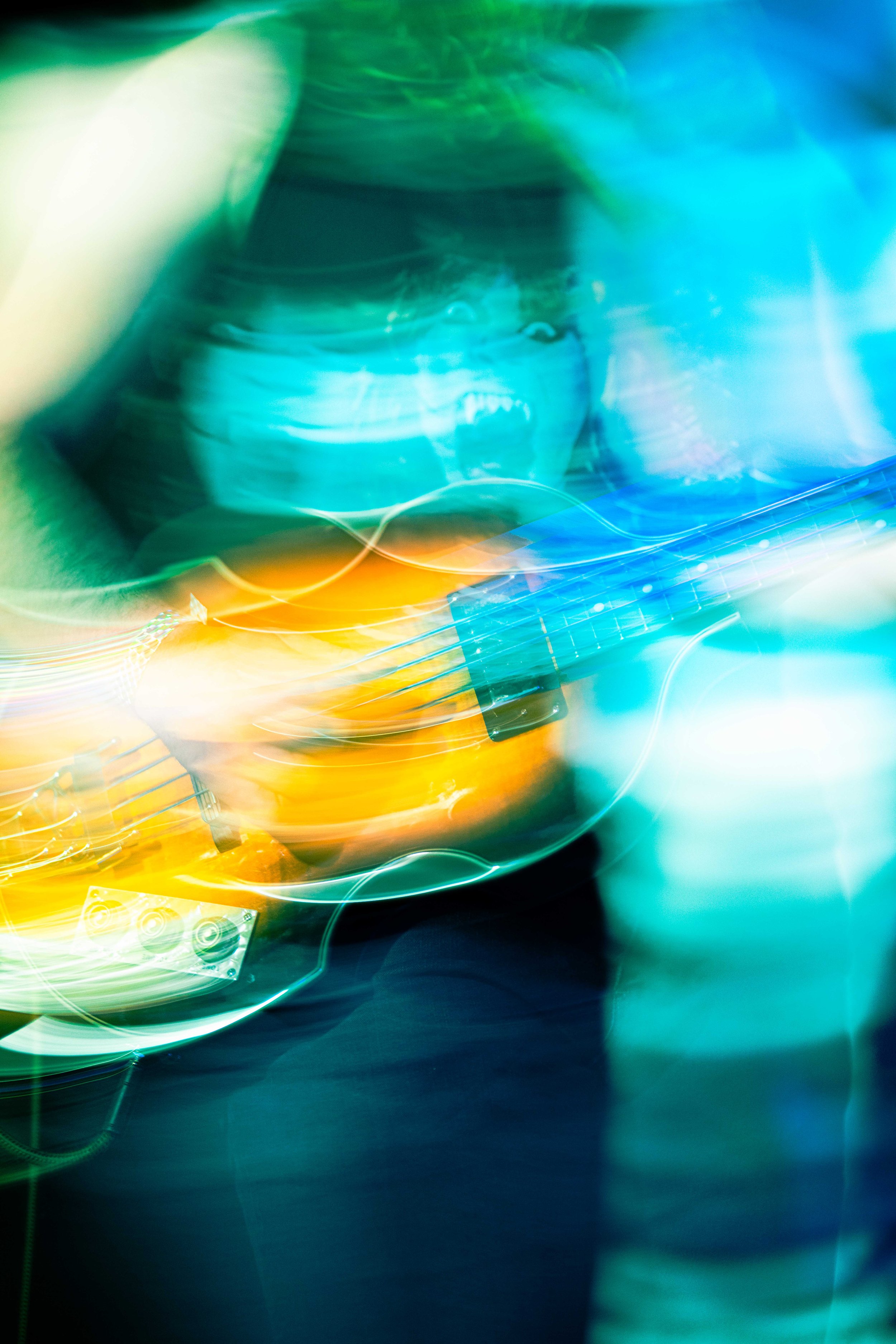 Colorful abstract image of a person playing an electric guitar with bright, blurred lights in the background.
