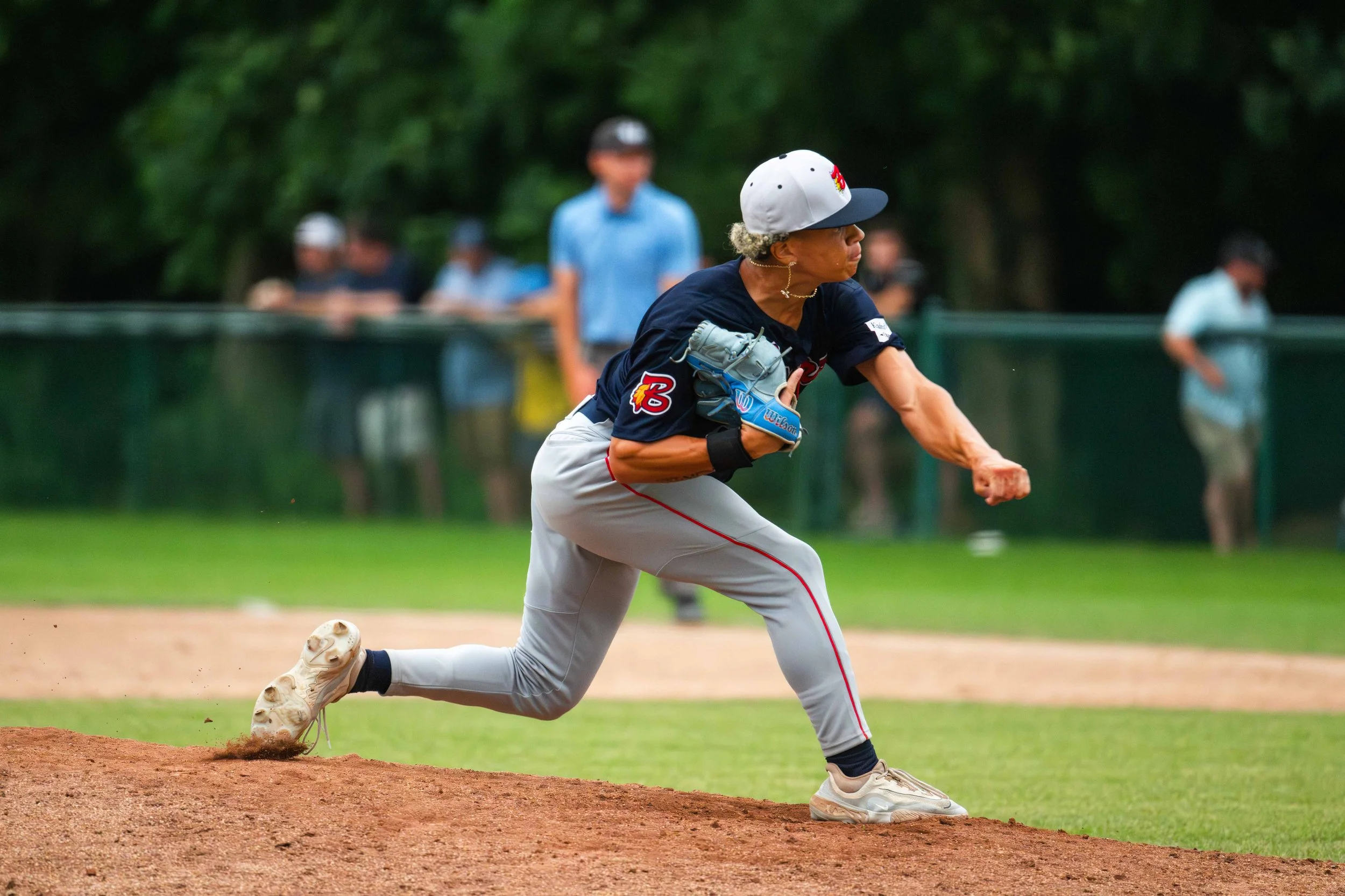 A man in a baseball uniform is running on the baseball field, clutching a glove, with spectators in the background.