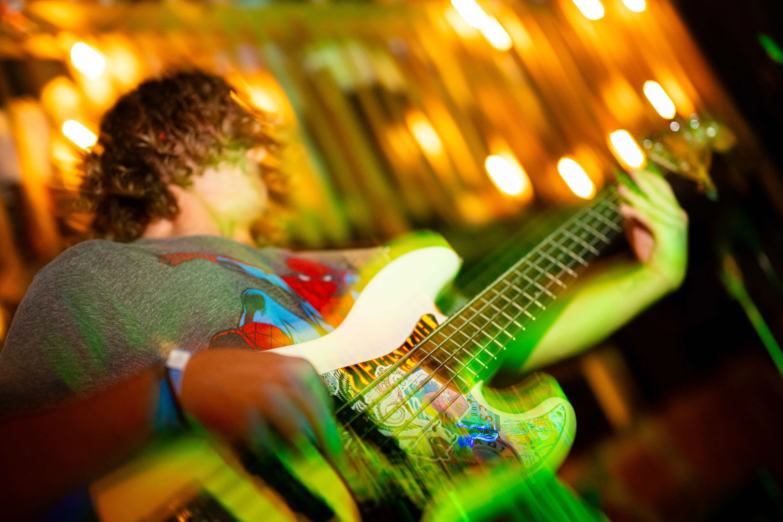 Person playing an electric guitar with colorful lighting and blurred background.