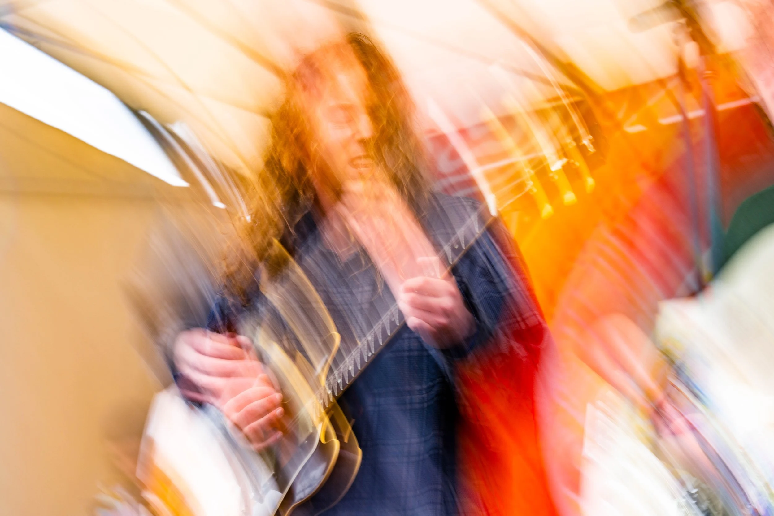 A person playing a guitar with a blurred, swirling background.