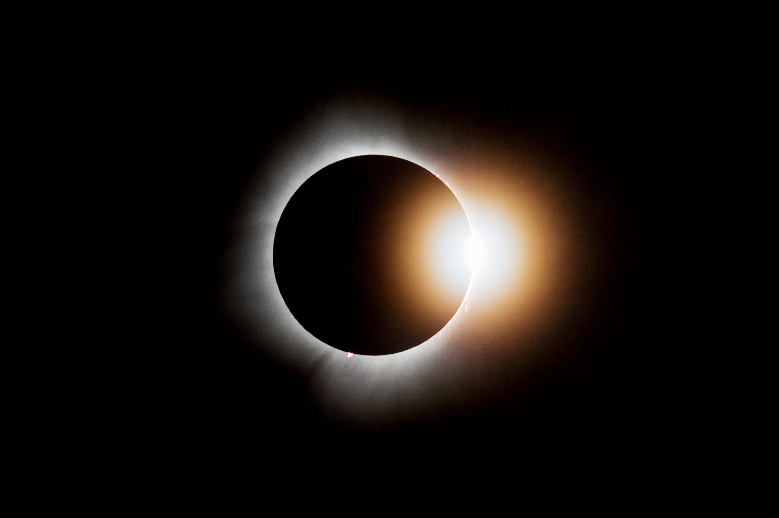 A solar eclipse with the moon covering the sun, creating a dark silhouette with a bright halo of light around the moon.