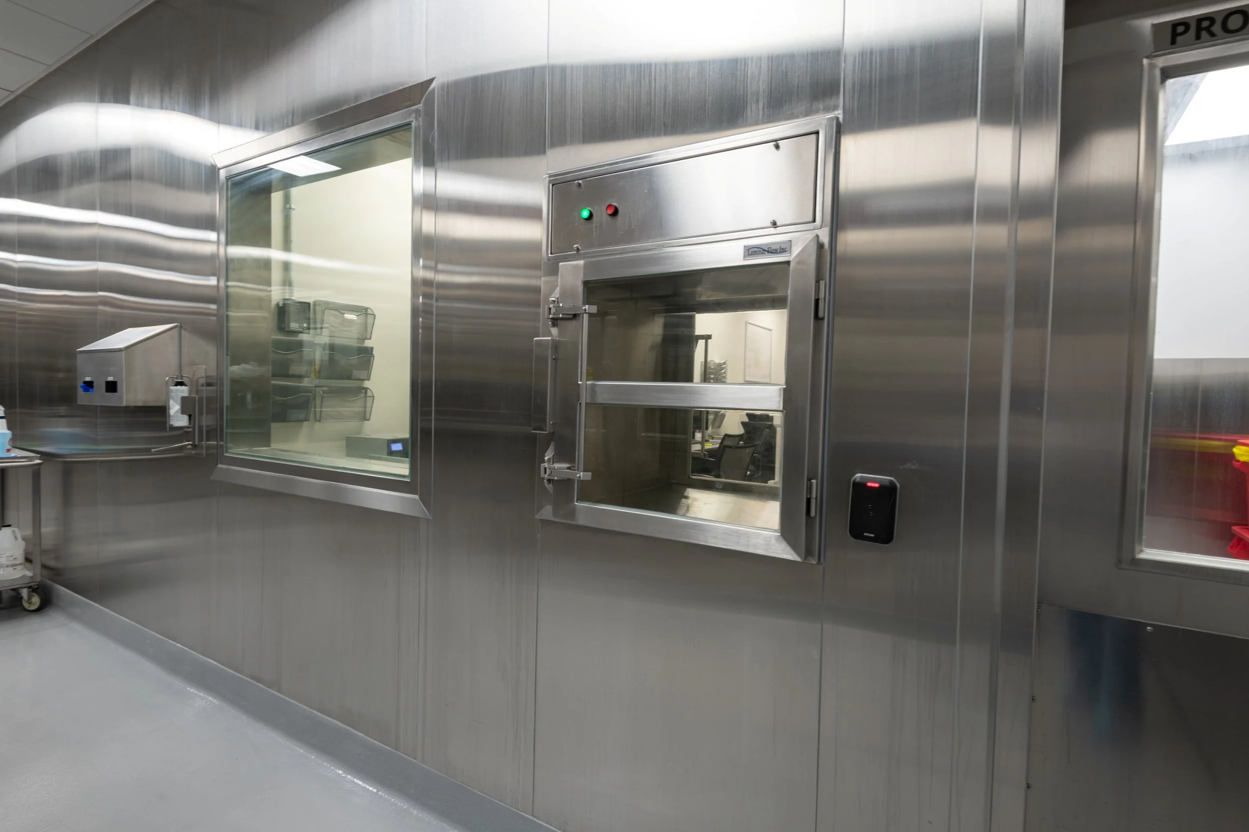Sterile hospital room with stainless steel pass-through windows and a galley door.