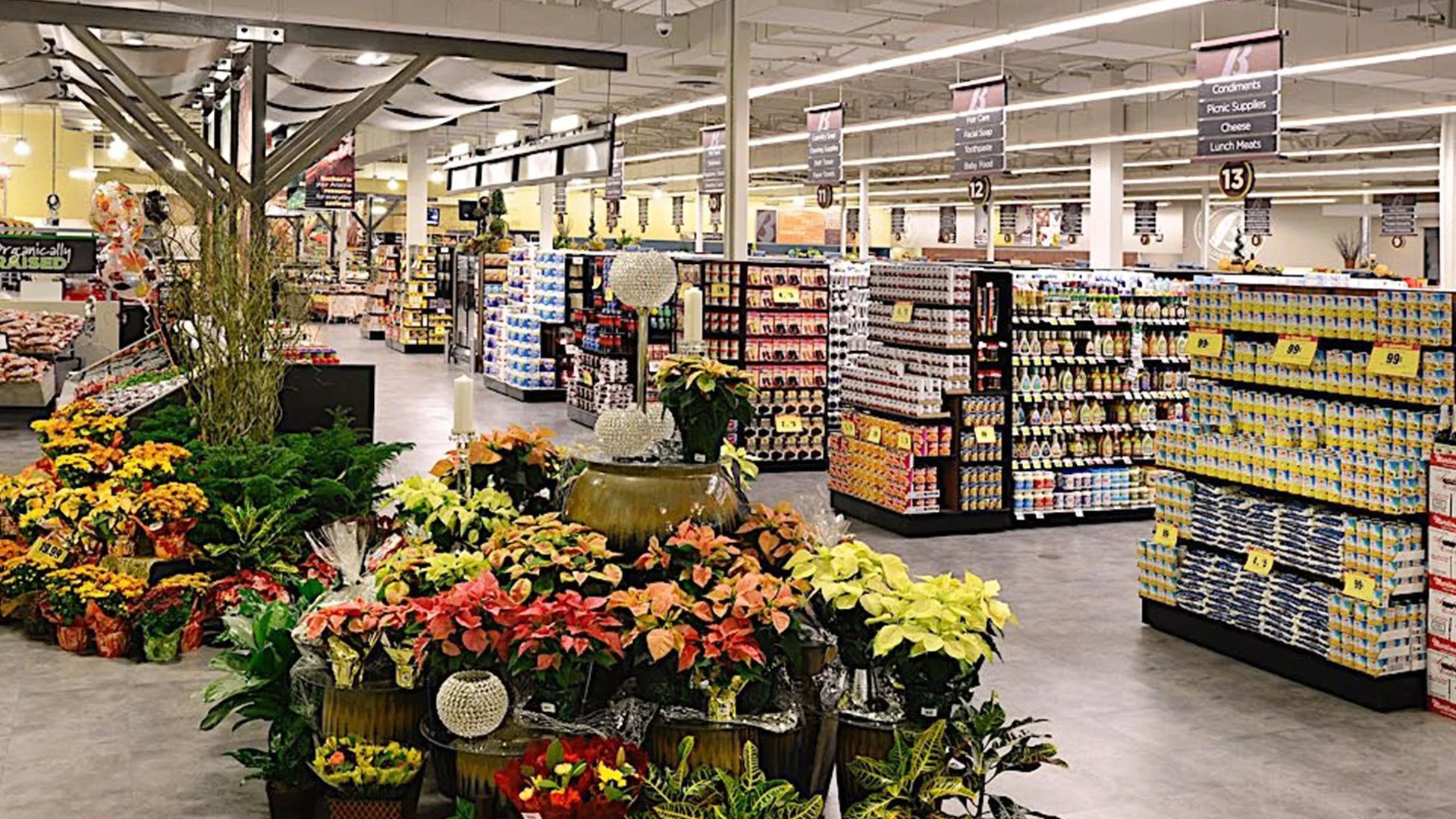Inside of a grocery store with flower displays in the foreground and various aisles of products in the background.