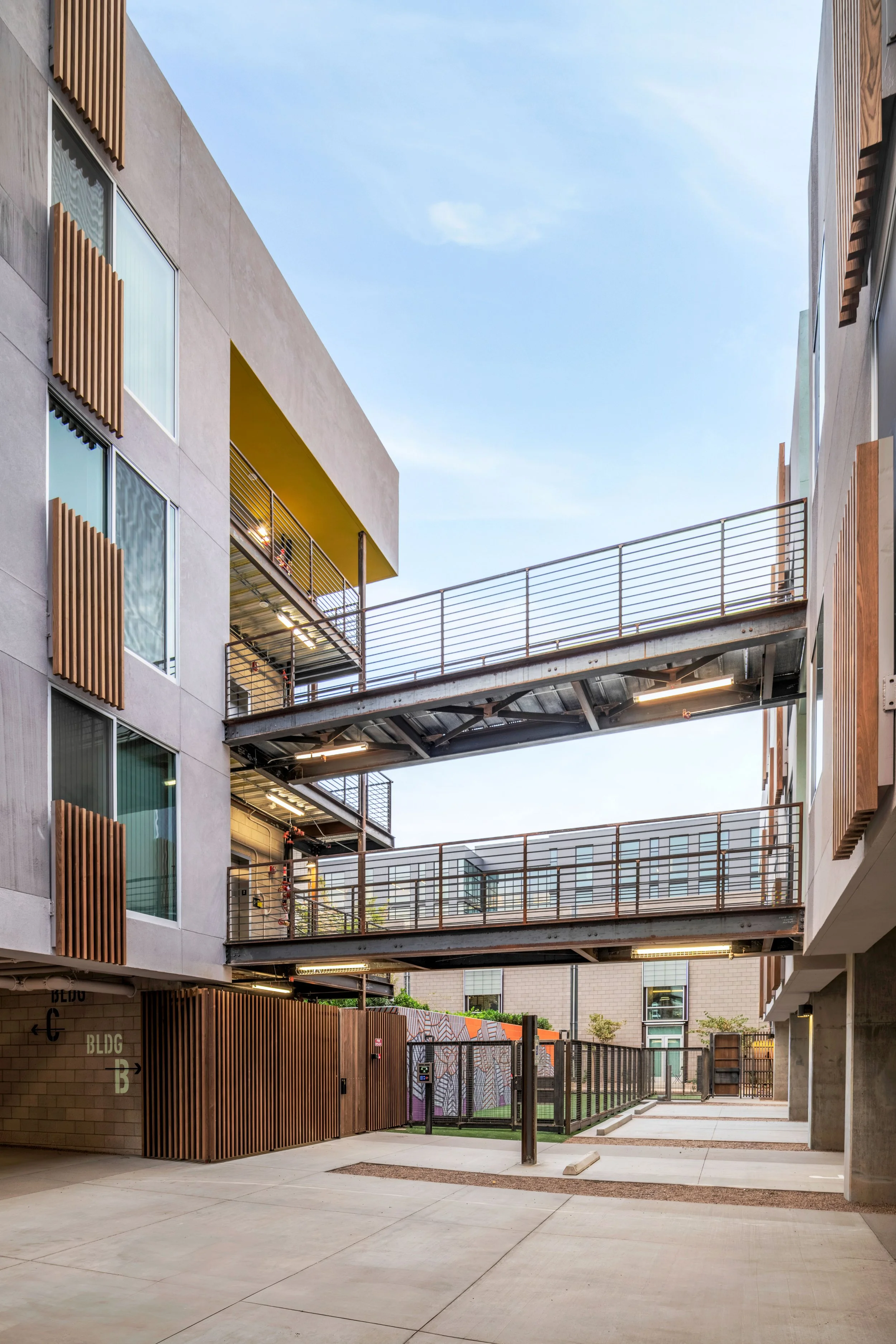 Modern multi-story apartment complex with exterior walkways and a courtyard.