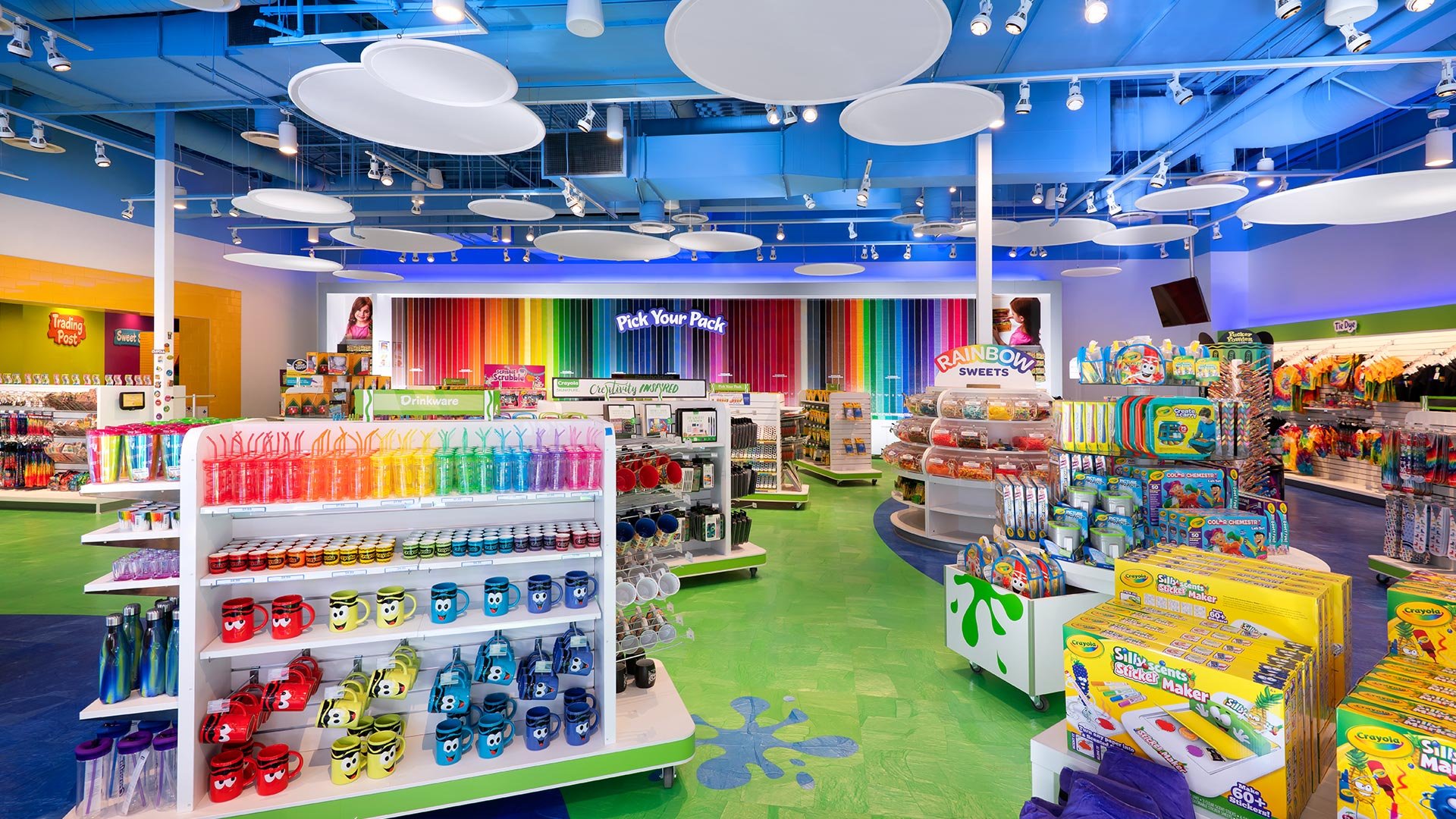 Interior of a colorful toy store with shelves of various toys, games, and art supplies, including rainbow-colored decor and playful signage.