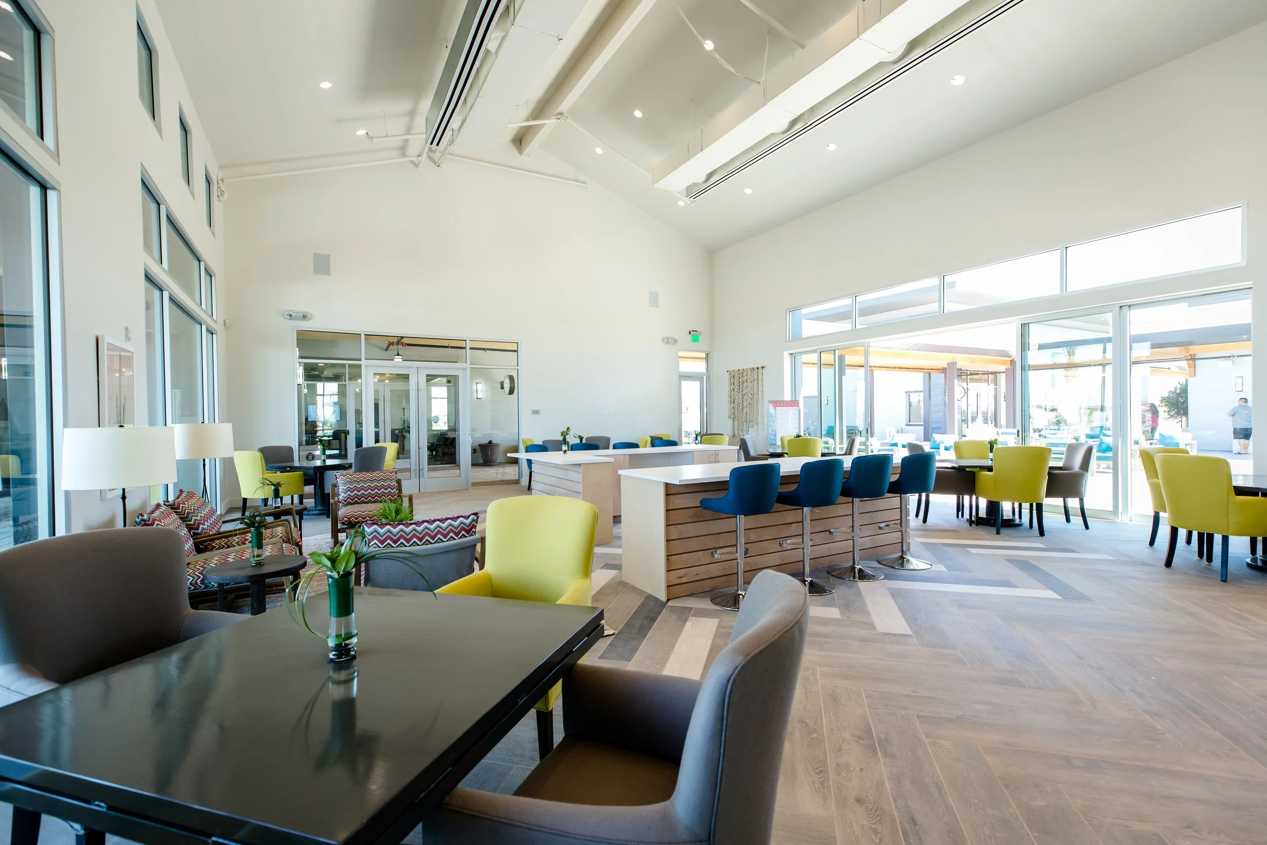 Bright, spacious indoor dining area with large windows, colorful chairs, tables, and bar seating.