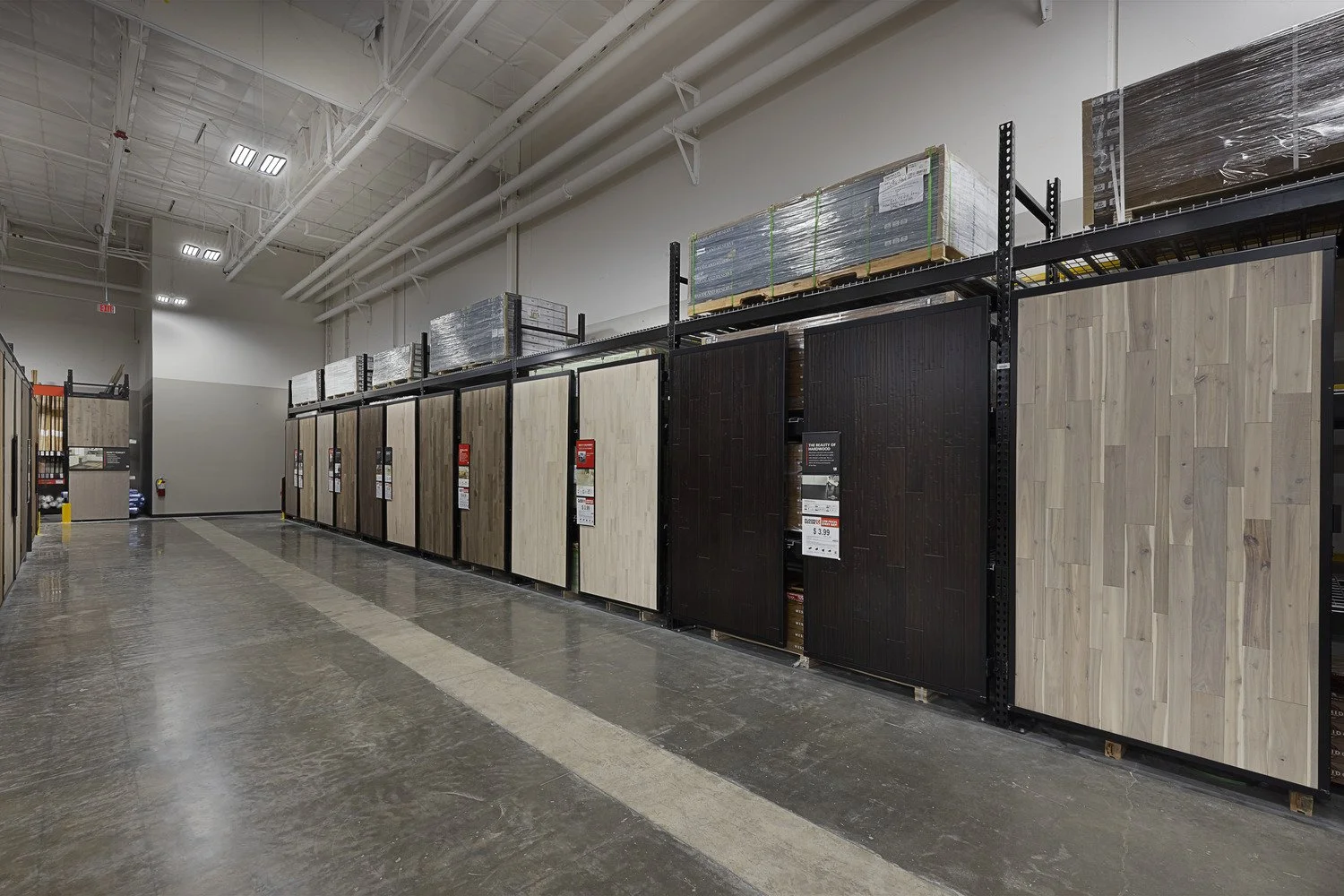 Aisle of wood flooring samples on display racks inside a store.
