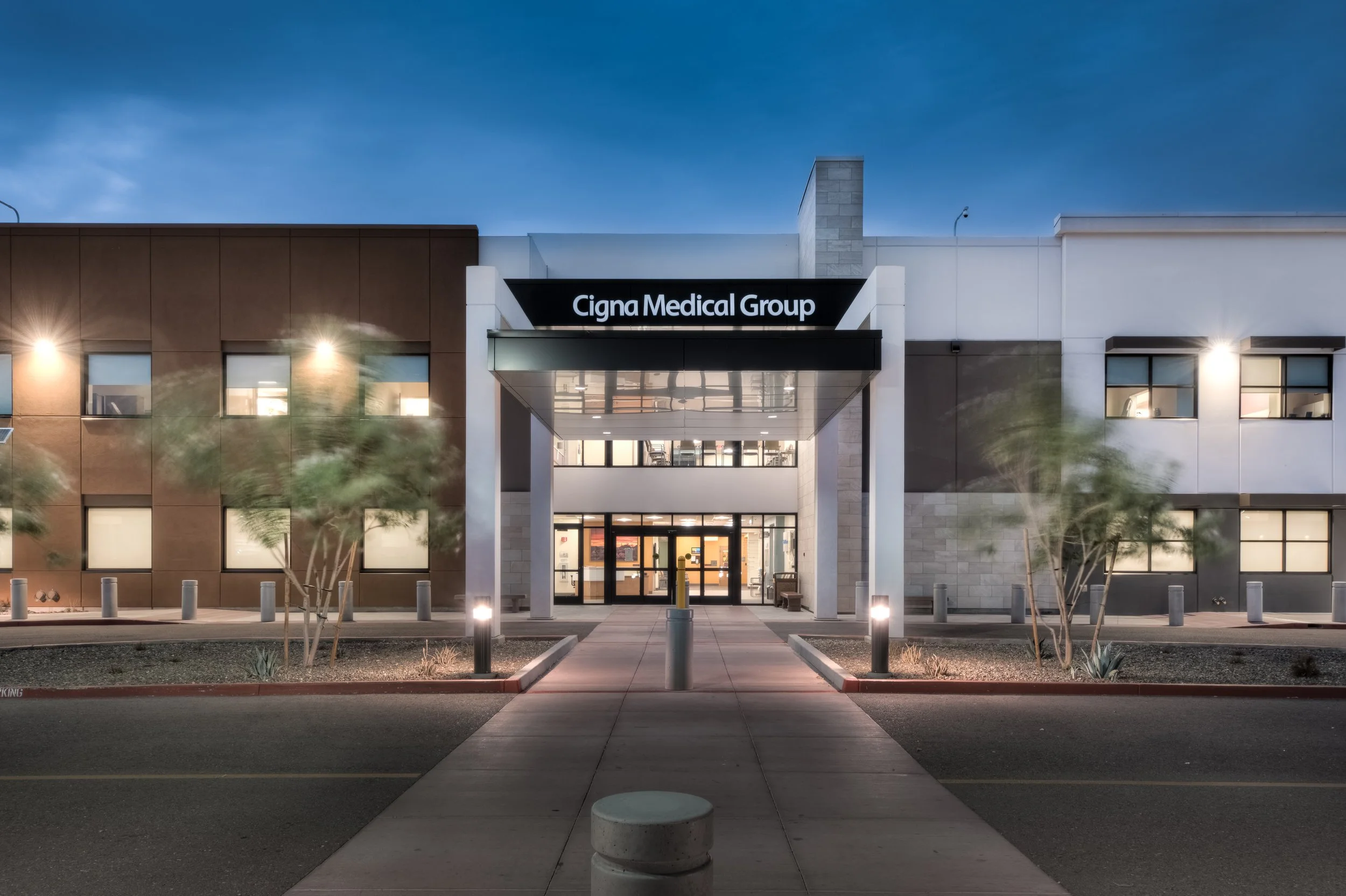 The exterior of Cigna Medical Group building at dusk, with well-lit entrance, modern architecture, and landscaped walkway.