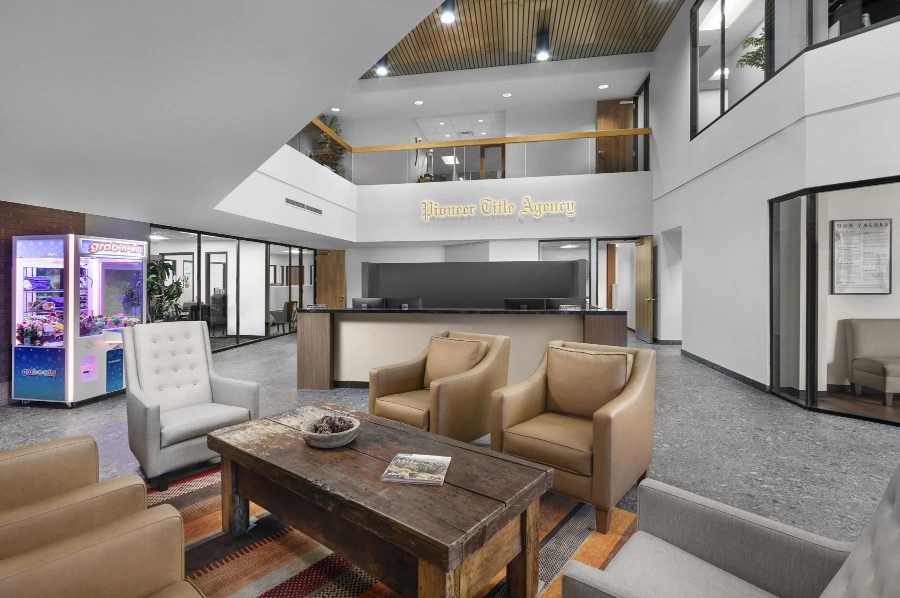 The lobby area of Pioneer Title Agency with seating chairs, a wooden coffee table, a claw machine toy, and a reception desk.