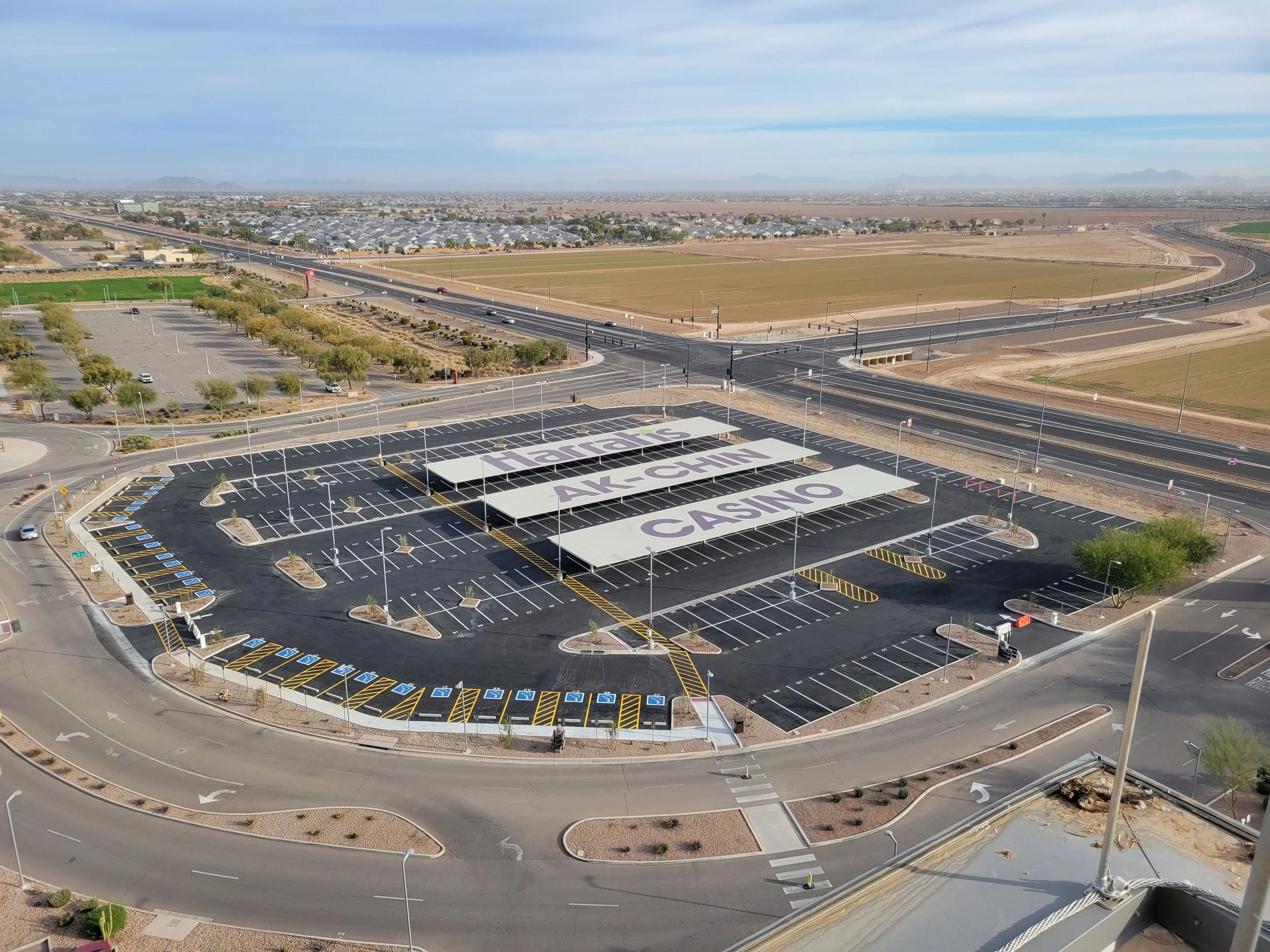 Empty parking lot with large signs on white panels spelling out 'Tiaras AK-CHIN CASINO' amid desert landscape, with roads and fields in the background.