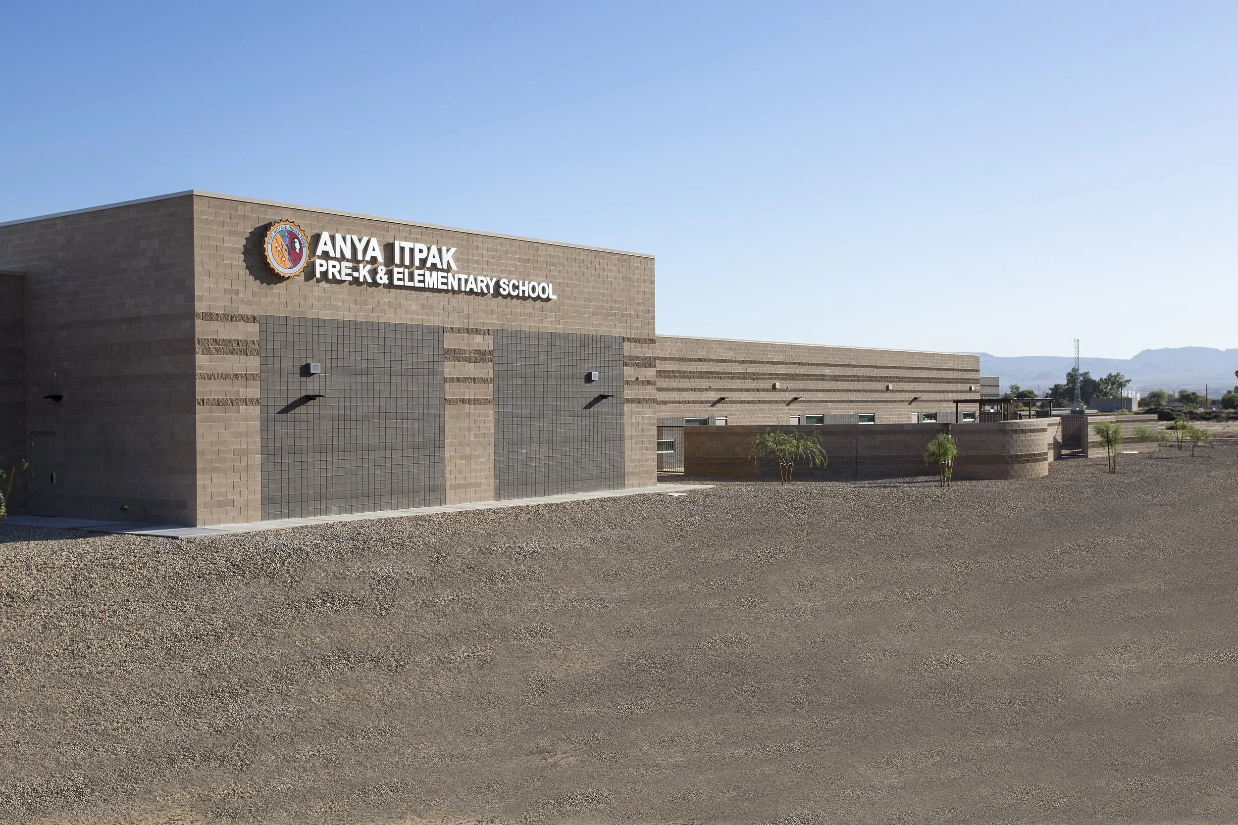 Exterior view of Anya Itpak Pre-K & Elementary School building with a clear blue sky and mountains in the background.