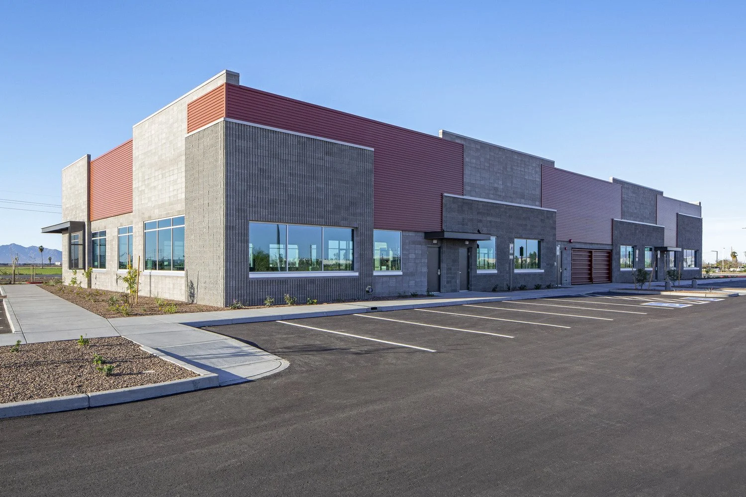 A modern, empty commercial building with large glass windows and a parking lot with marked spaces.