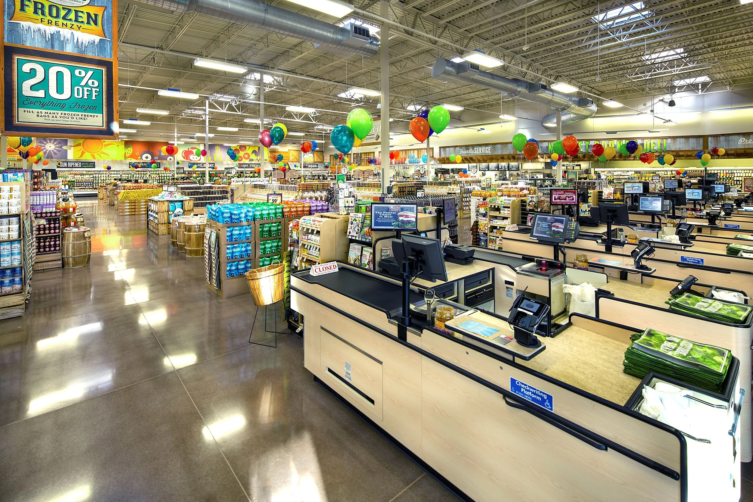 Interior of a grocery store with checkout counters, colorful balloons, and shelves stocked with various products.