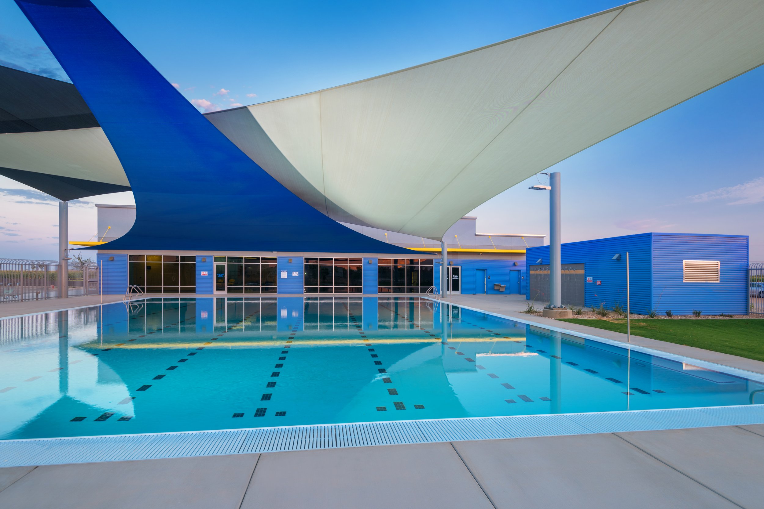 Empty swimming pool with lane markers under a colorful modern canopy structure at a recreational facility