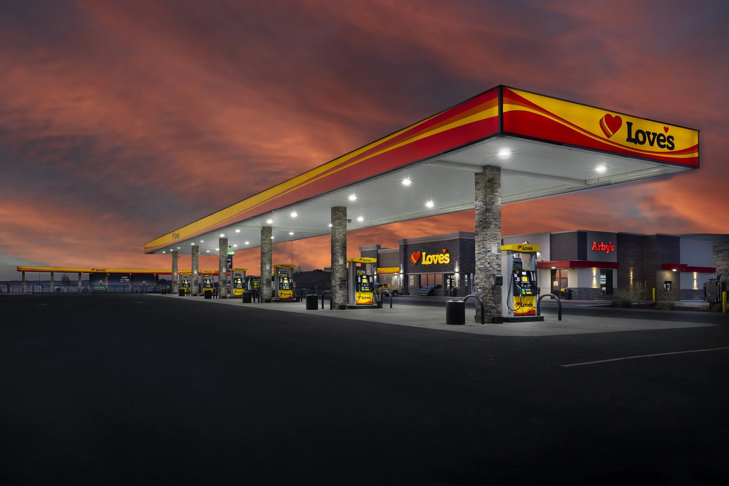 A Love's gas station and convenience store at sunset with a vibrant orange and pink sky.