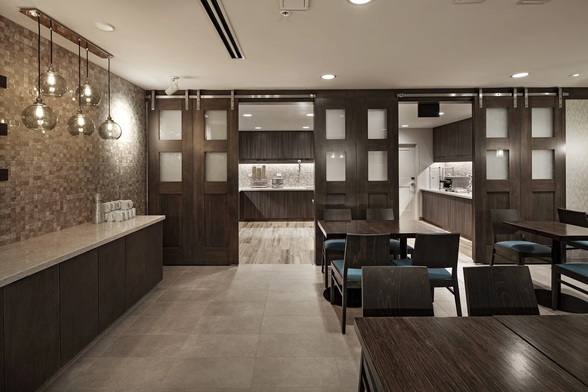 Interior of a restaurant with dark wood furniture, tiled walls, and pendant lighting