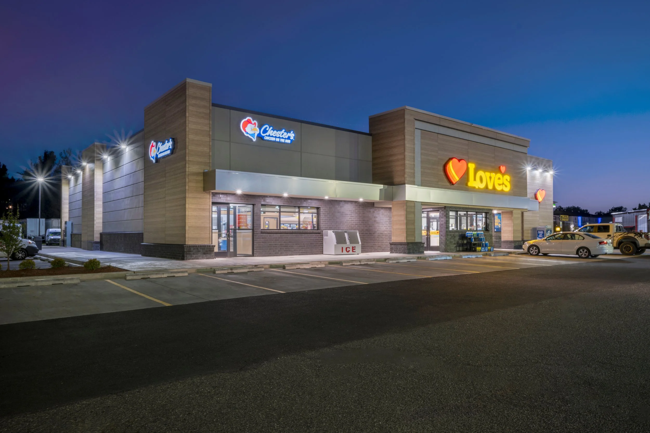 Nighttime view of a Love's travel stop with bright signage, parked cars, and a clean parking lot.