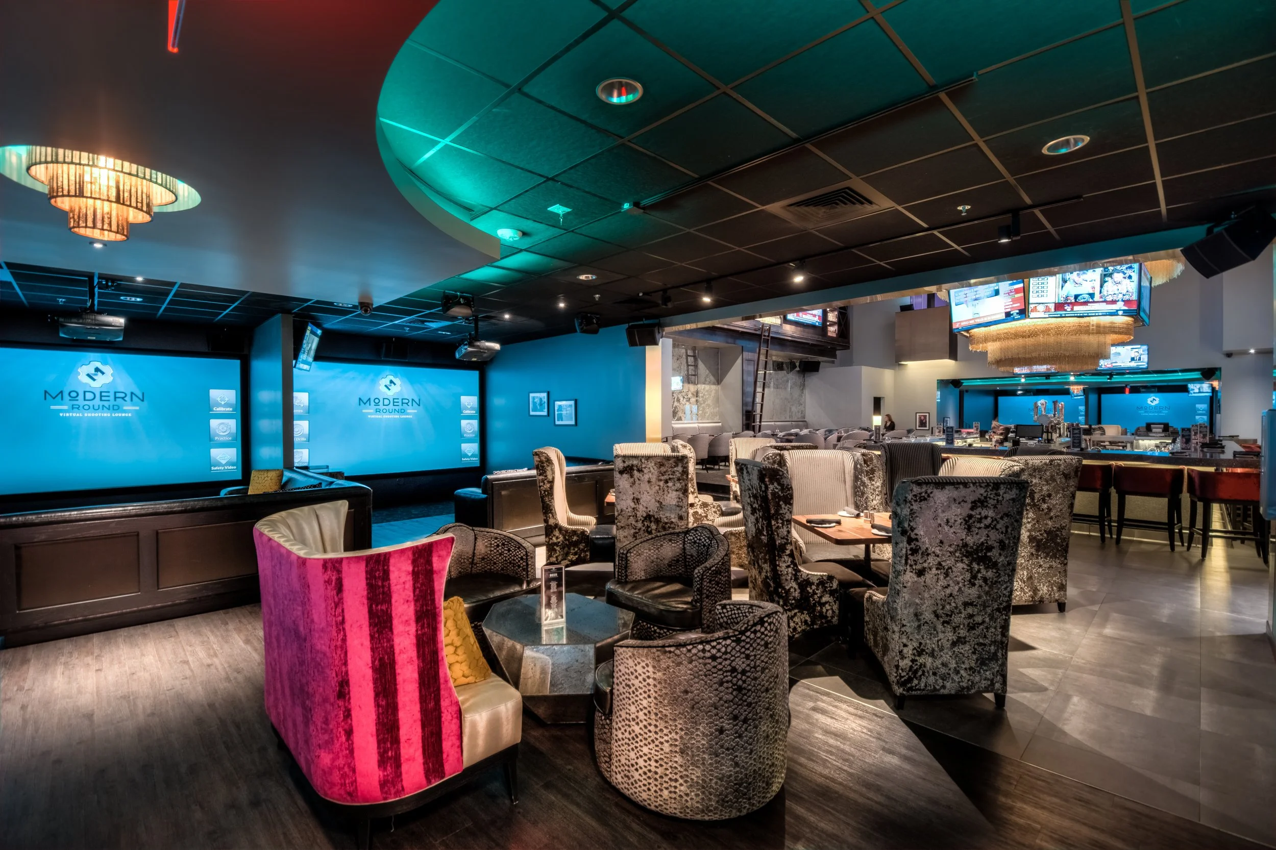 Interior of a modern lounge or bar with multiple chairs, a bar counter, and large screens displaying a logo that reads 'Modern Round'.