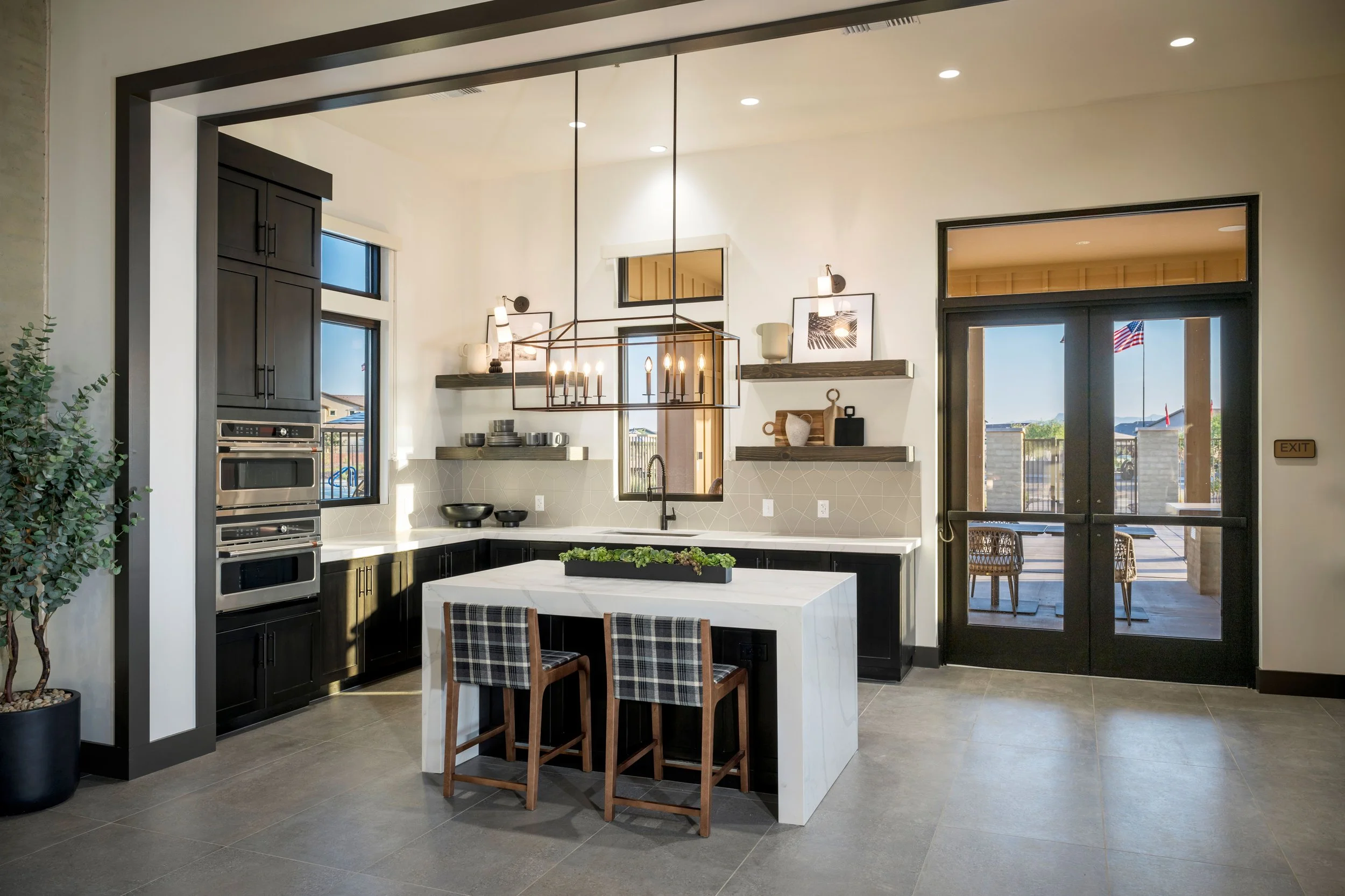 Modern kitchen with black and white cabinetry, an island with barstools, open shelves, and a view of a patio with an American flag outside