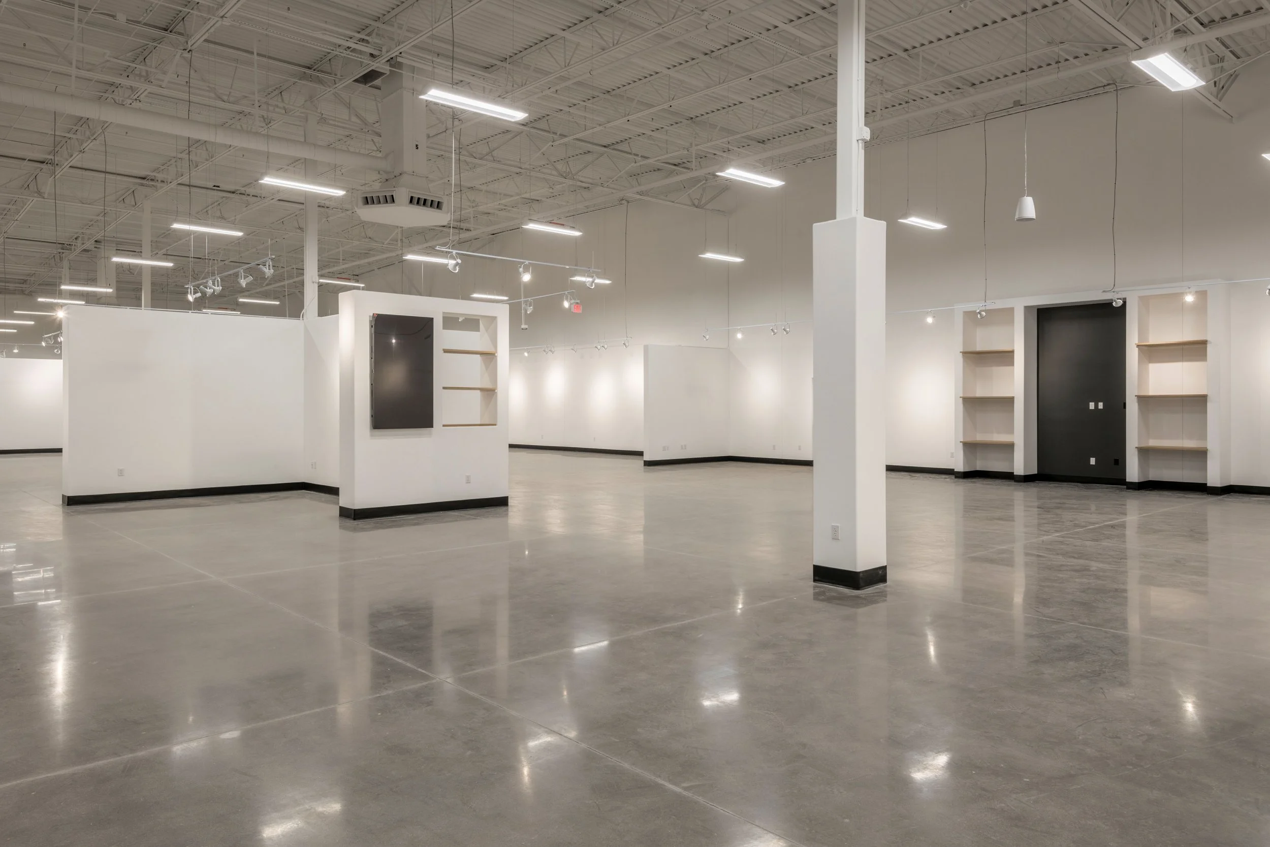 Empty art gallery with white walls, polished concrete floors, and ceiling lights.