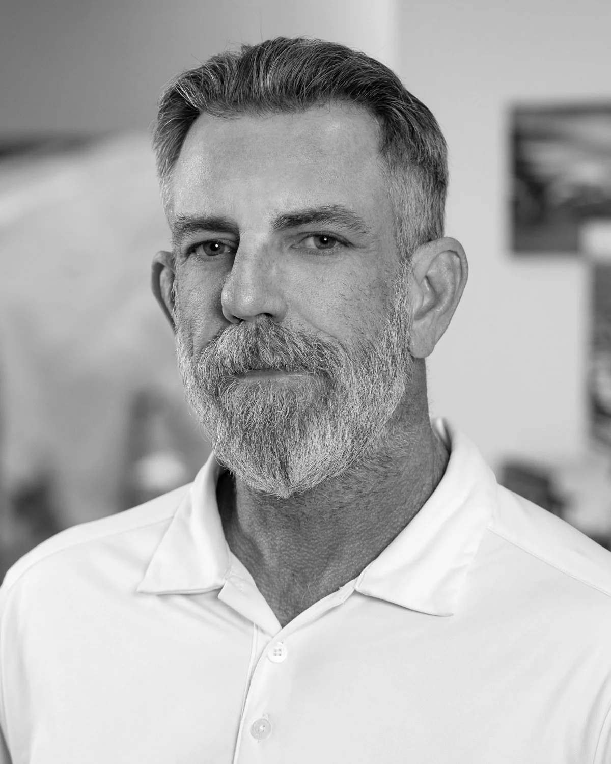 Black and white portrait of Ray Reves, Vice President of Field Operations at A.R. Mays Construction, wearing a collared shirt, in an indoor setting.
