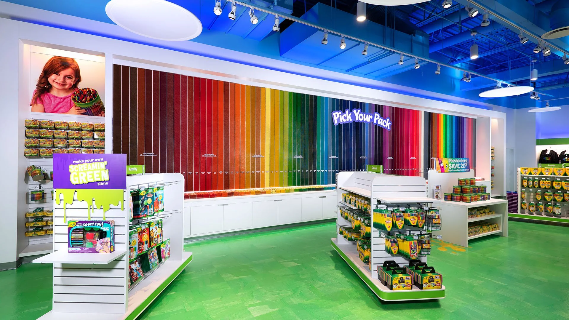 Colorful retail store interior with rainbow paint swatches, display shelves with art supplies, and a sign reading 'Pick Your Pack'.