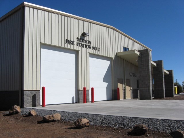 Exterior of a fire station with two large garage doors, a small entrance door, and a sign that reads 'Vemon Fire Station No. 2'