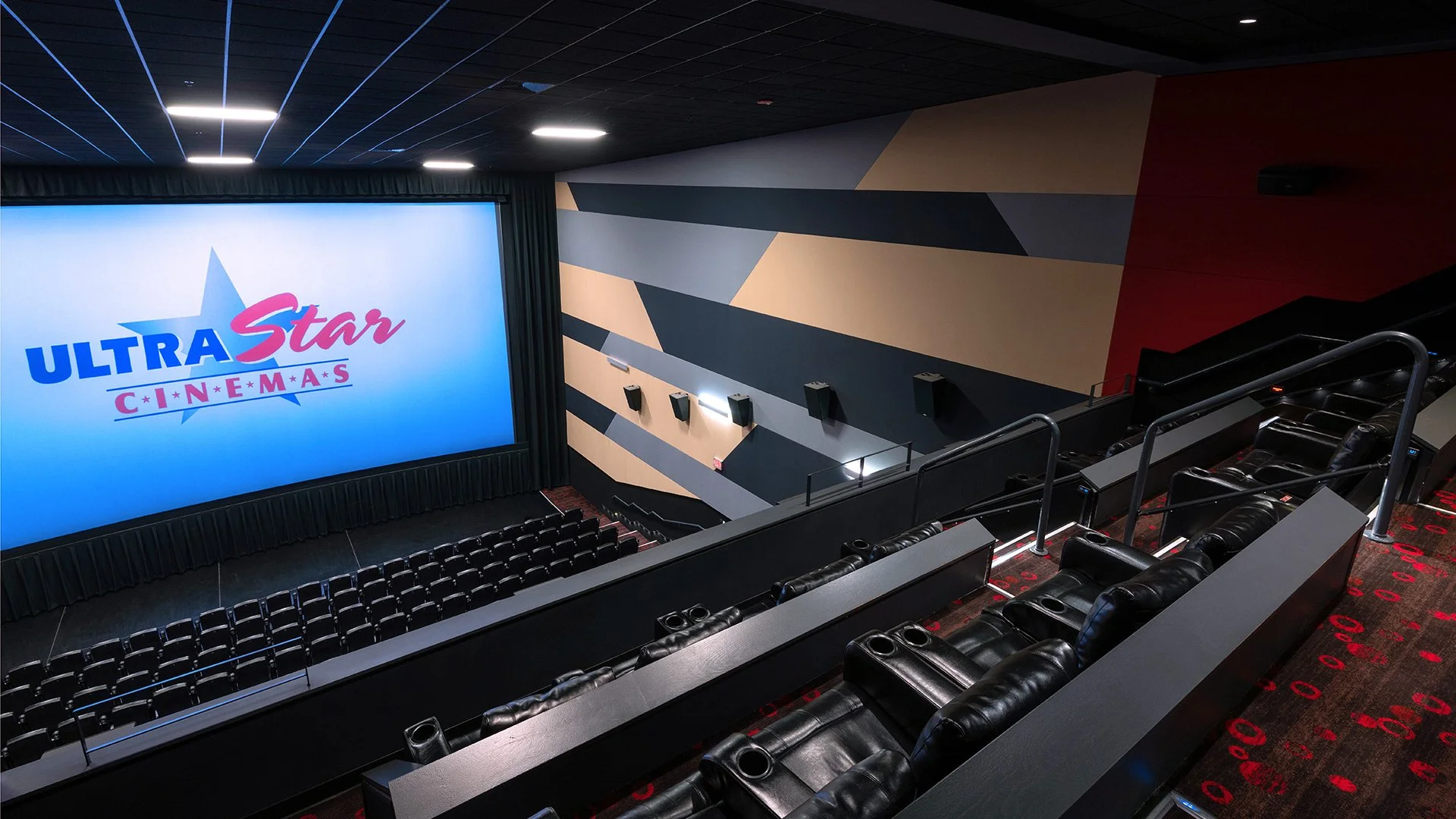 Interior of a modern movie theater with a large screen displaying the ULTRA Star CINEMAS logo, black leather chairs, and colorful geometric wall art.