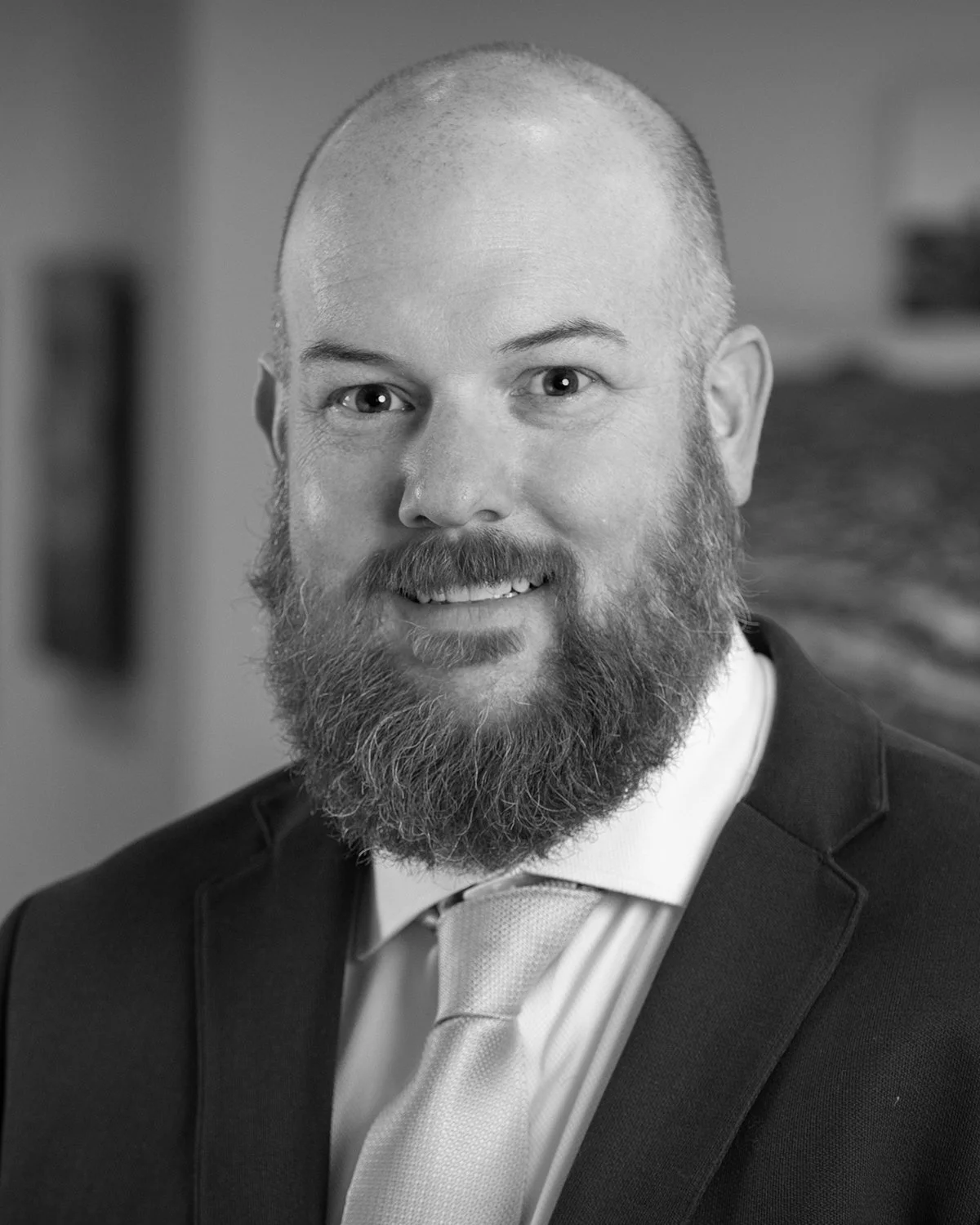 Black and white headshot of Matt Ringer, Vice President of Construction at A.R. Mays Construction, wearing a suit and tie, smiling at the camera.