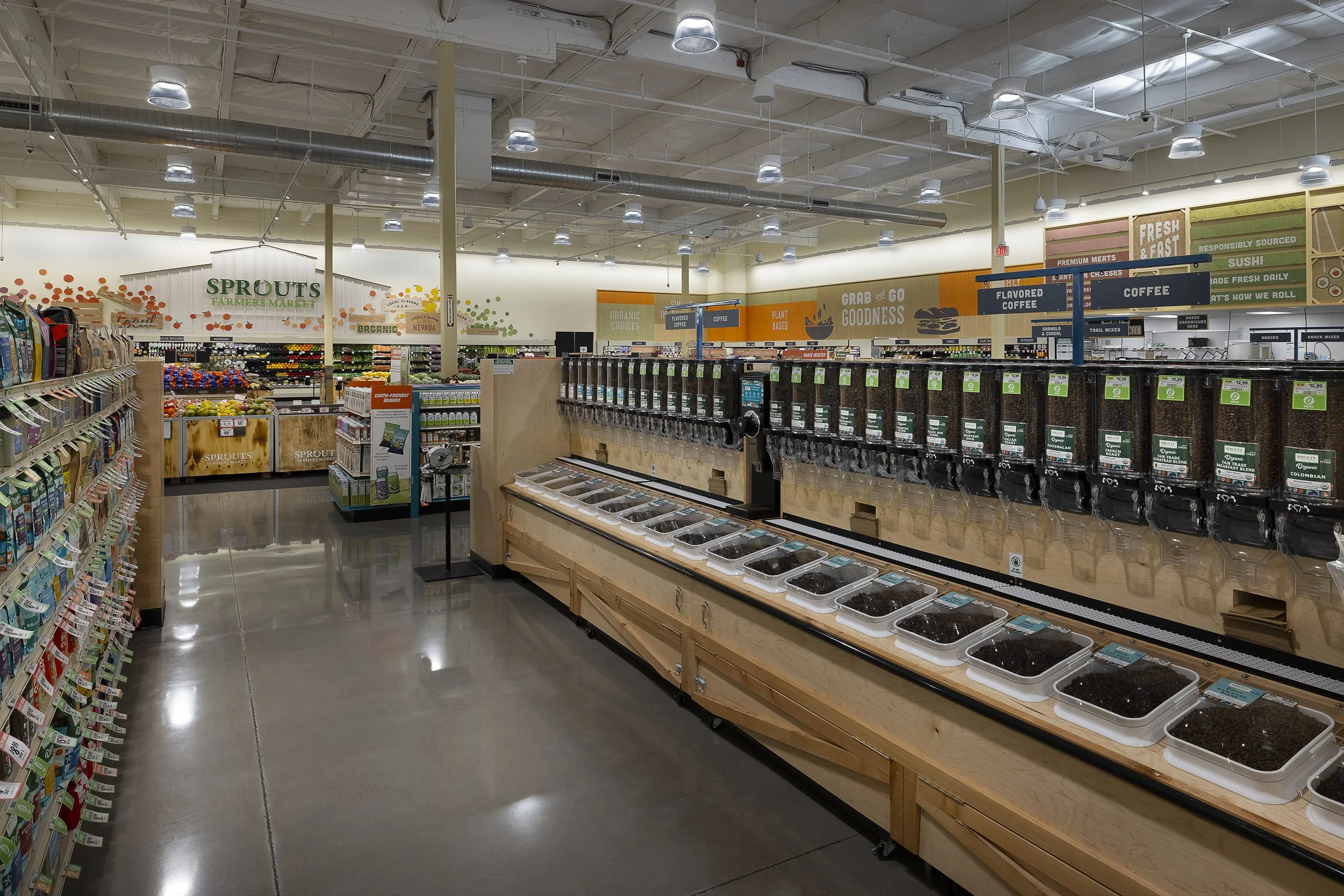 Interior of a grocery store with bulk coffee dispensers and organized produce section in the background.