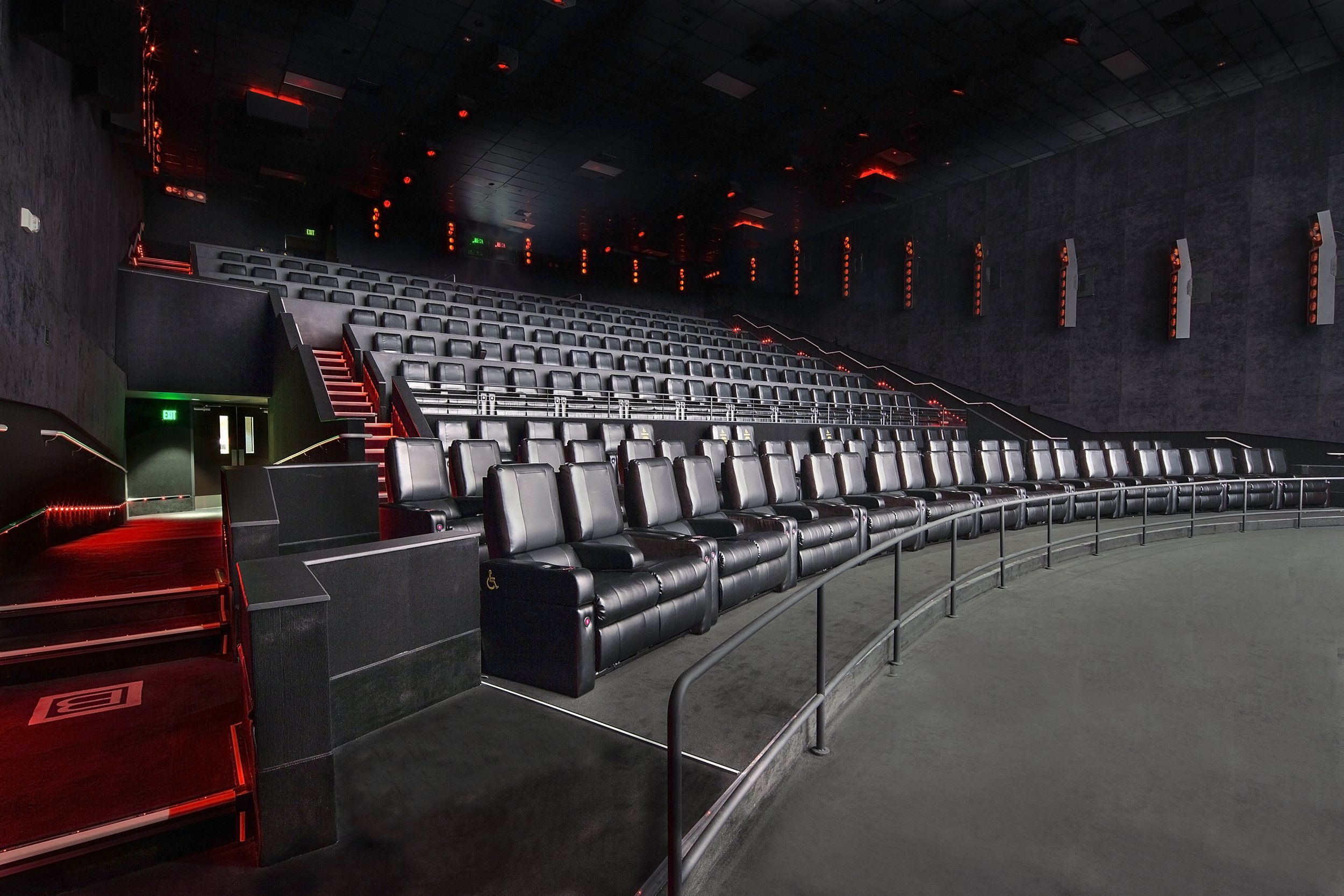 Theater with black leather seats and red lighting accents in a dark room.