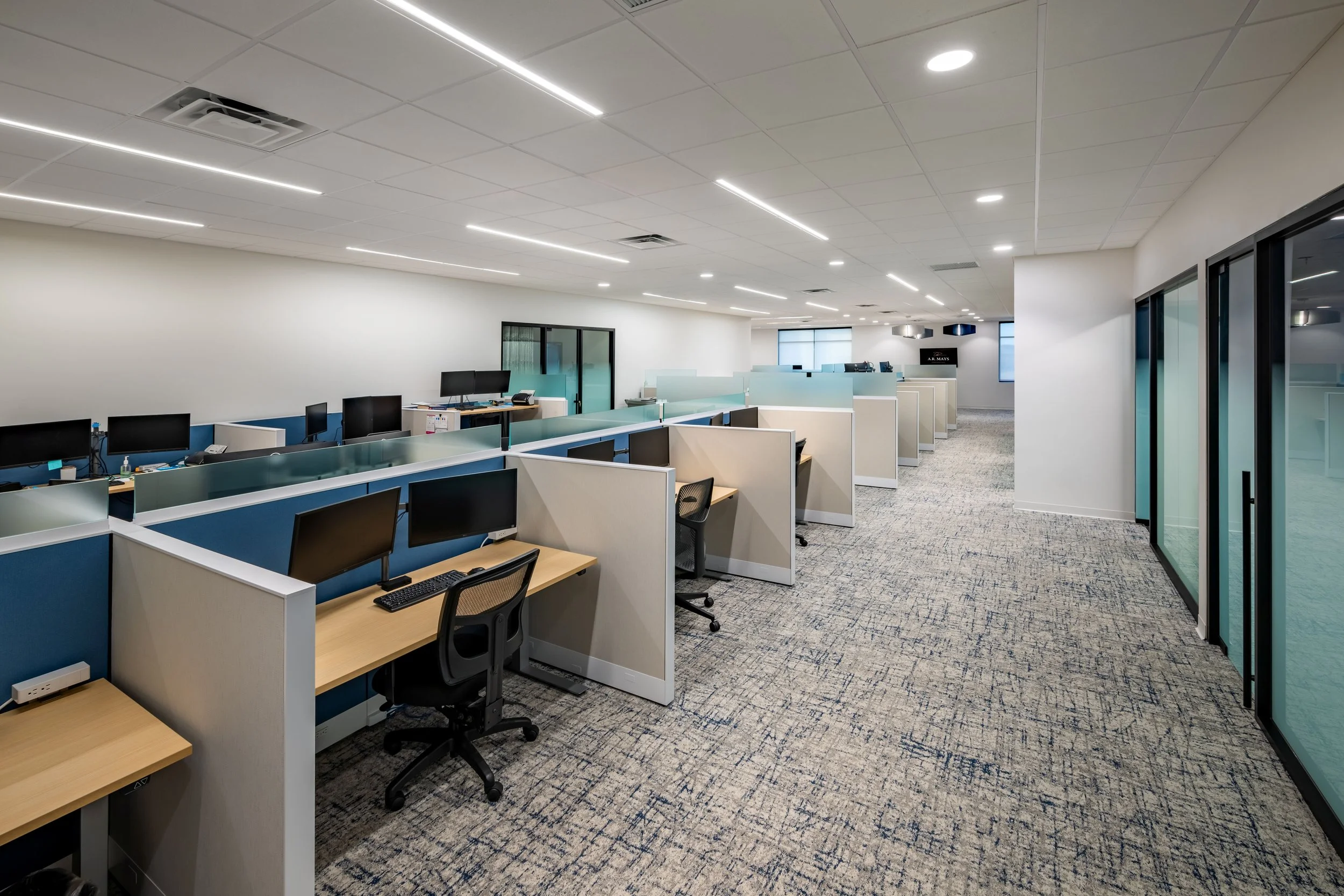 Empty call center with cubicles, computers, and office chairs in a modern workspace.